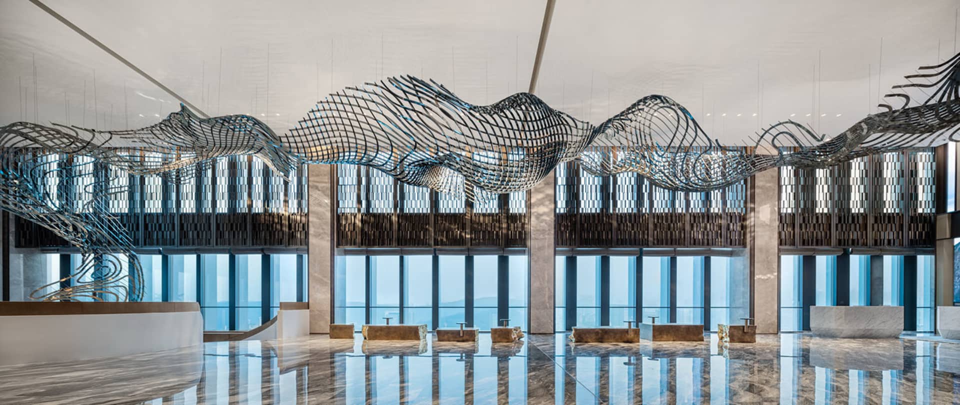 A modern lobby interior featuring a large, intricate metal sculpture