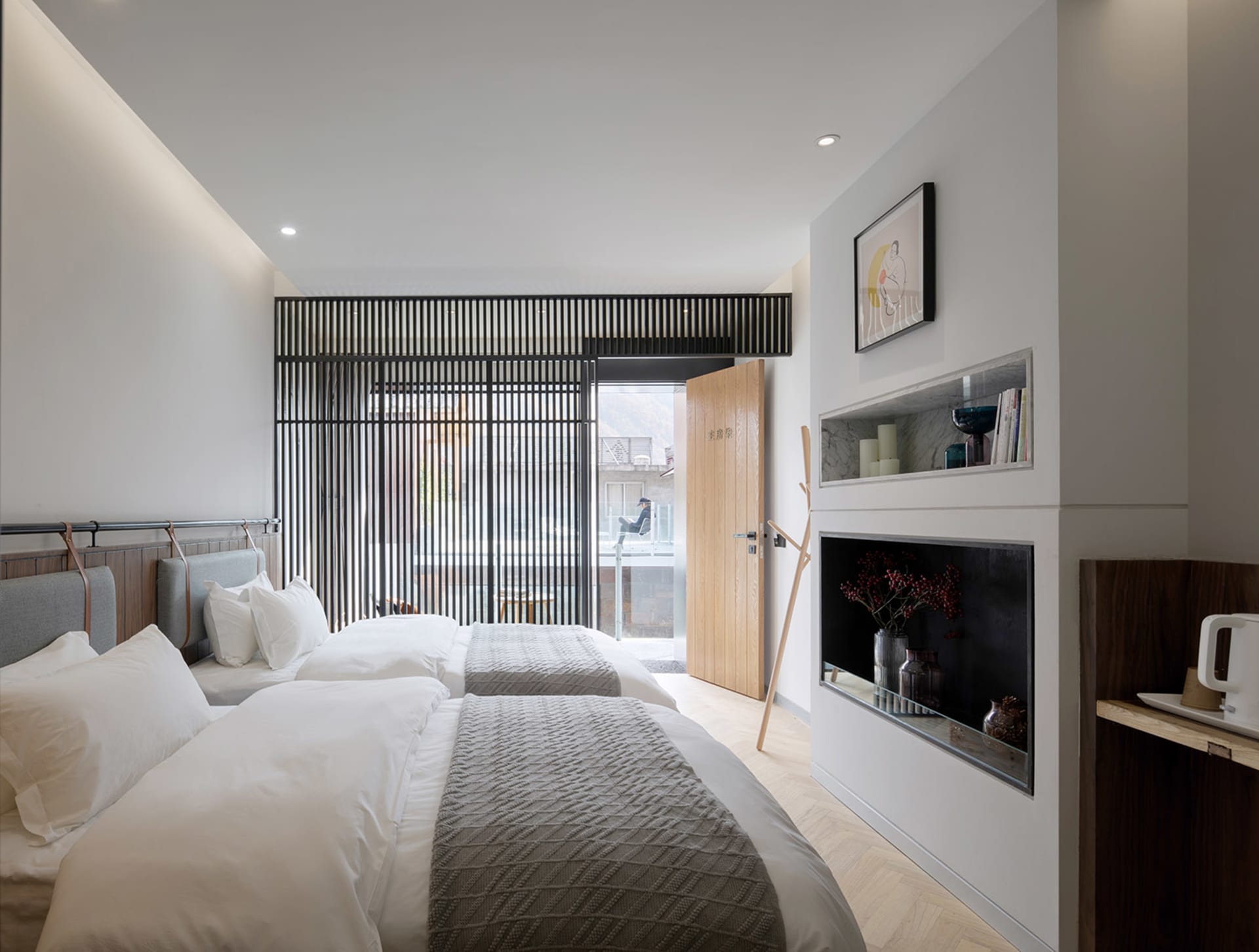 A modern minimalist hotel room with wooden furniture, metal accents, and glass doors.