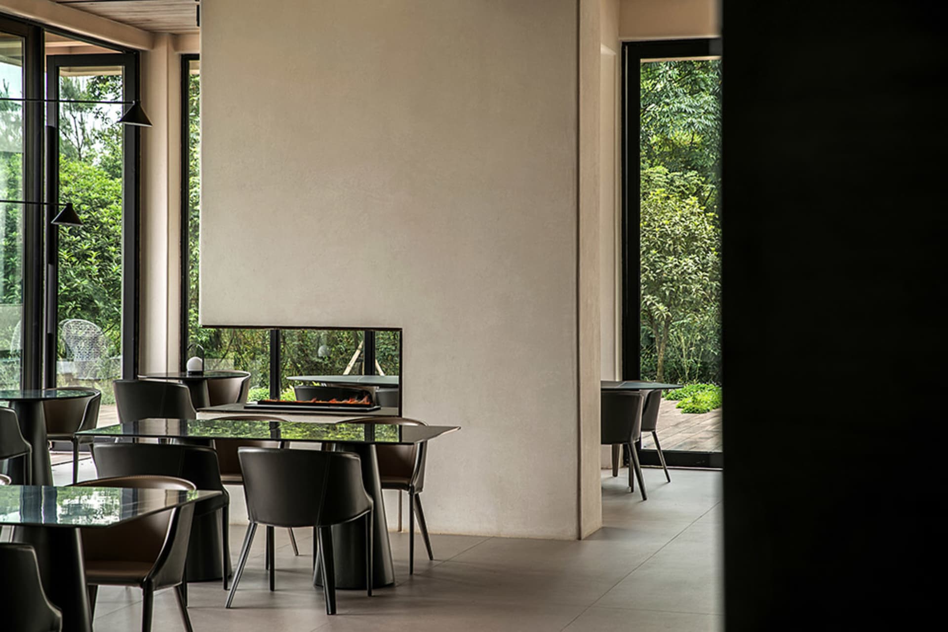 Modern interior of a restaurant featuring glass tables, metal chairs, and wooden flooring.
