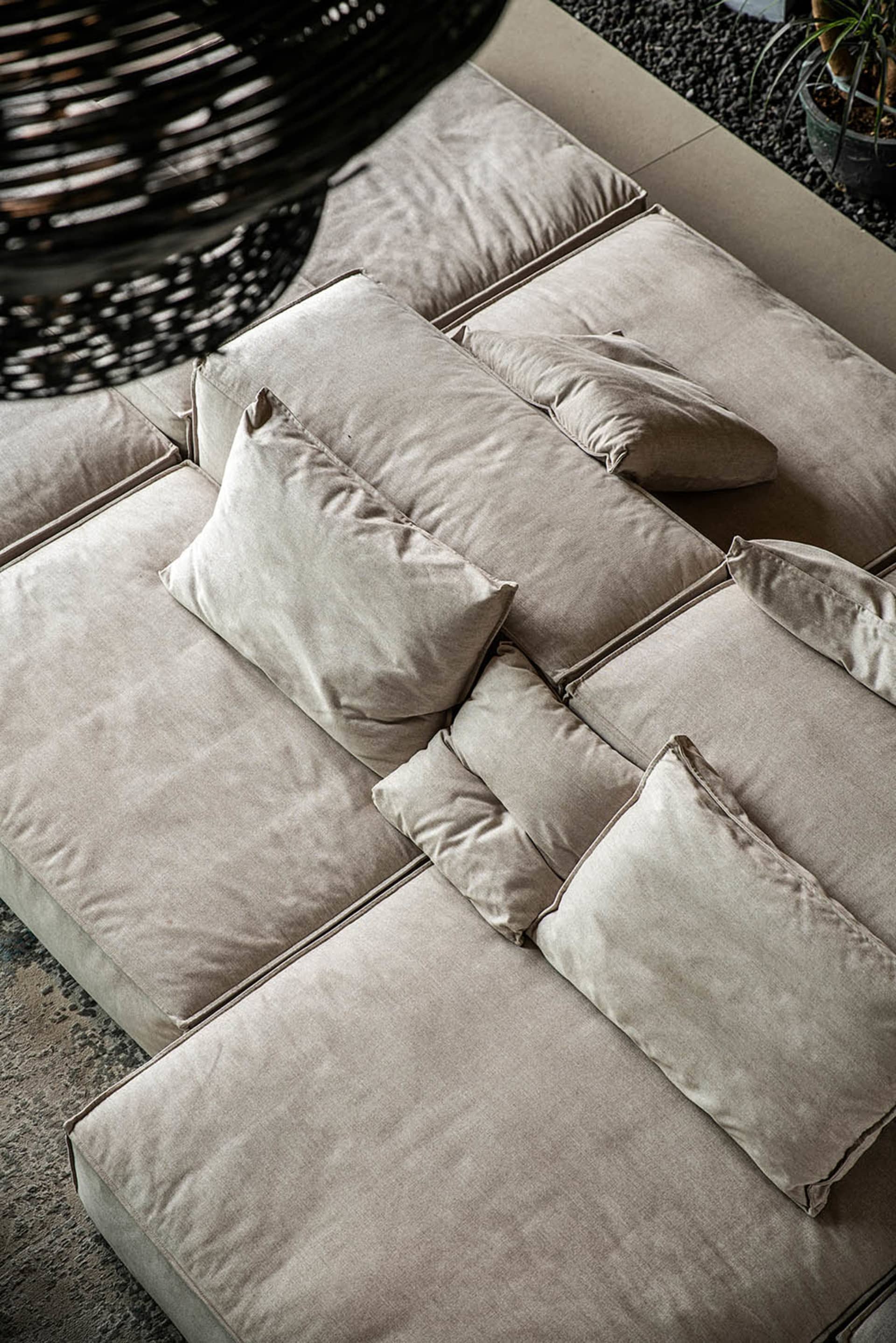 Plush, light gray fabric sofa adorned with multiple cushions in a modern design.