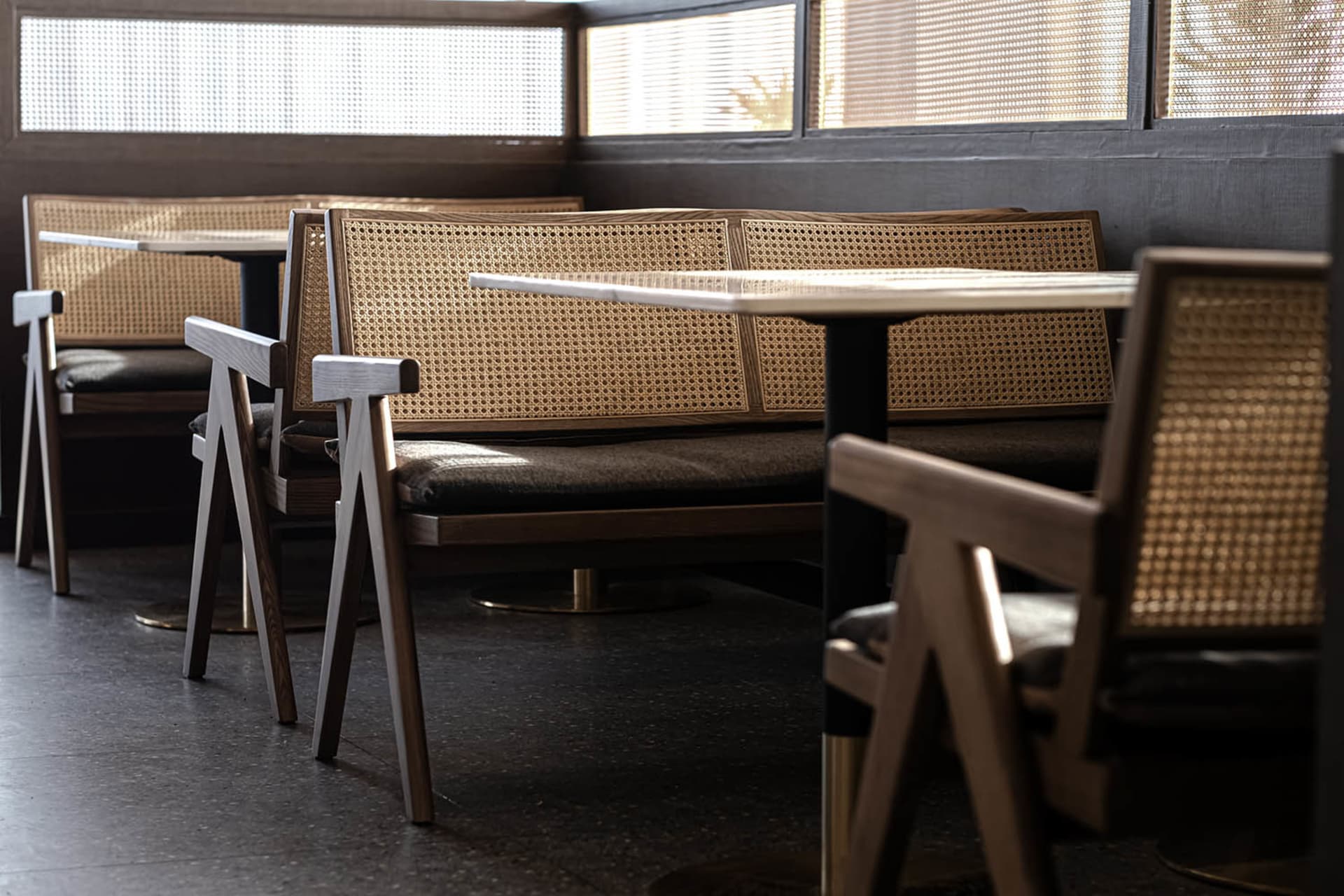 Industrial-style seating with cane backs and metal frames in a restaurant setting.