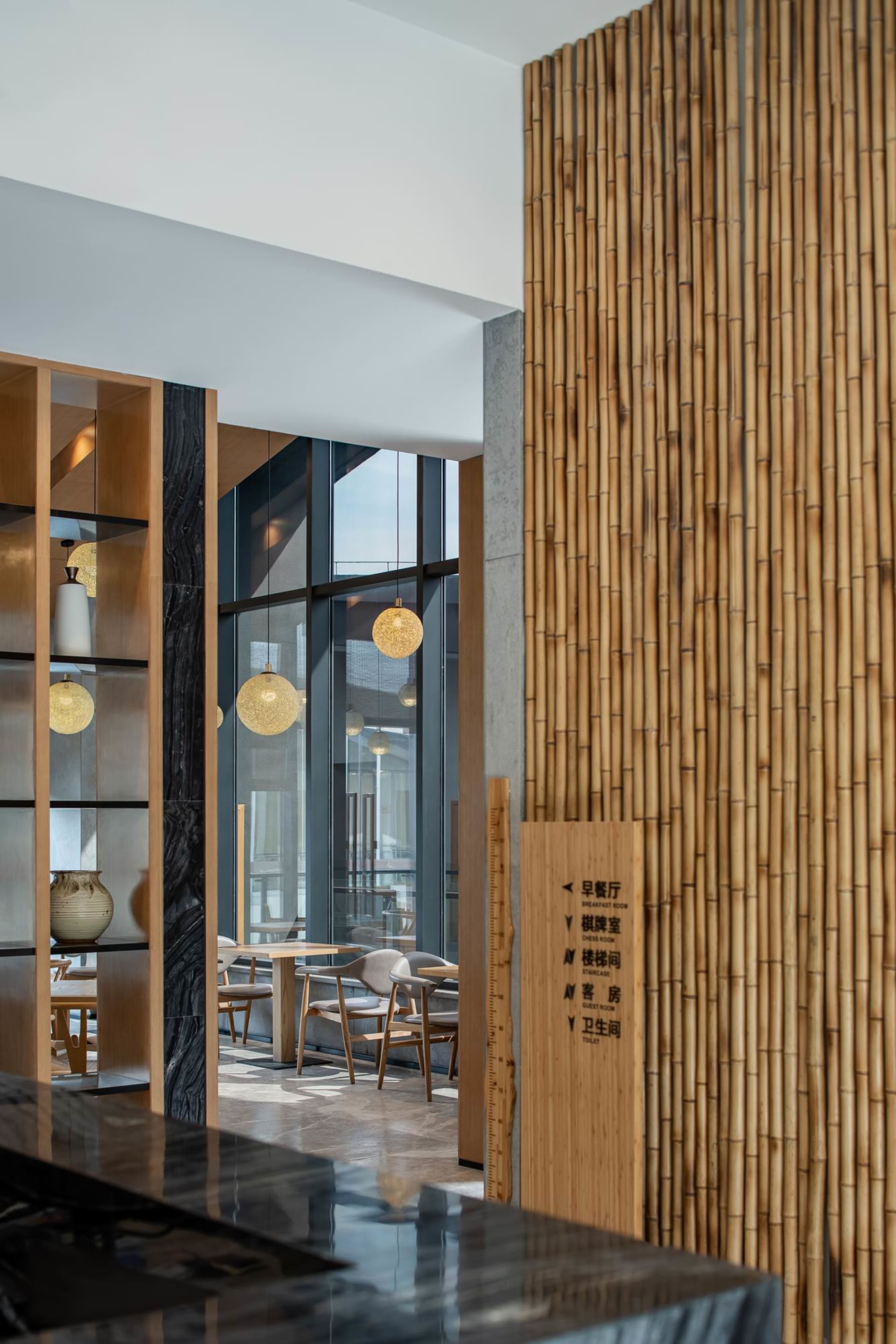 Minimalist cafe interior with wooden seating, glass partitions, and marble finishes.