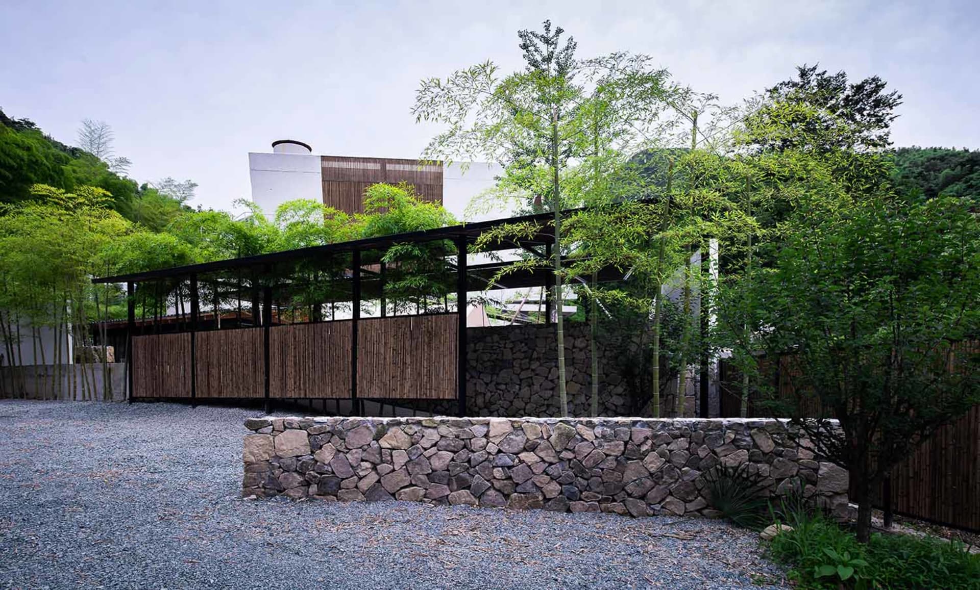A modern landscape design featuring stone walls and a gravel path.