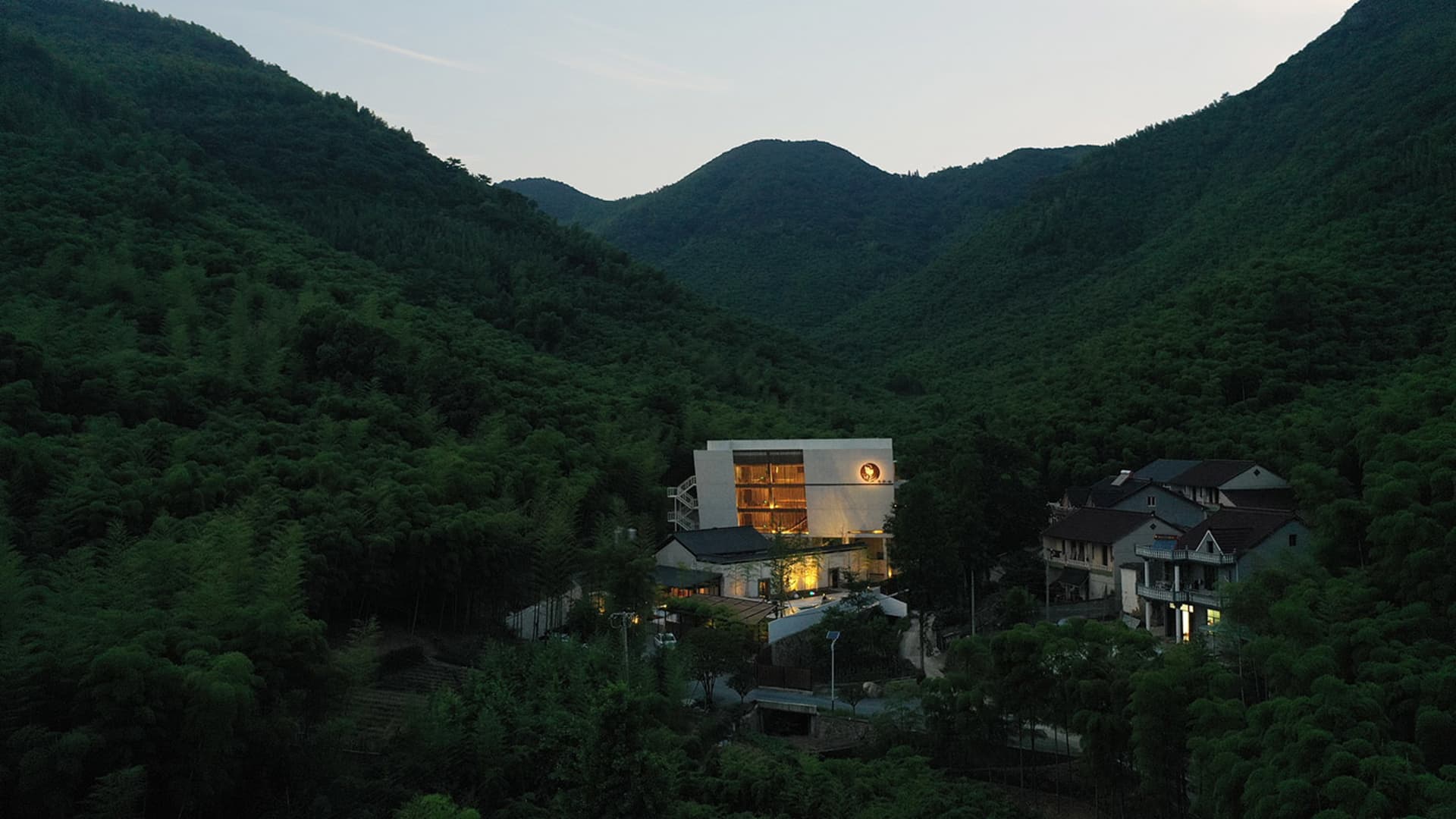 一座優雅的現代住宅建築，坐落於鬱鬱蔥蔥的綠色山谷中。