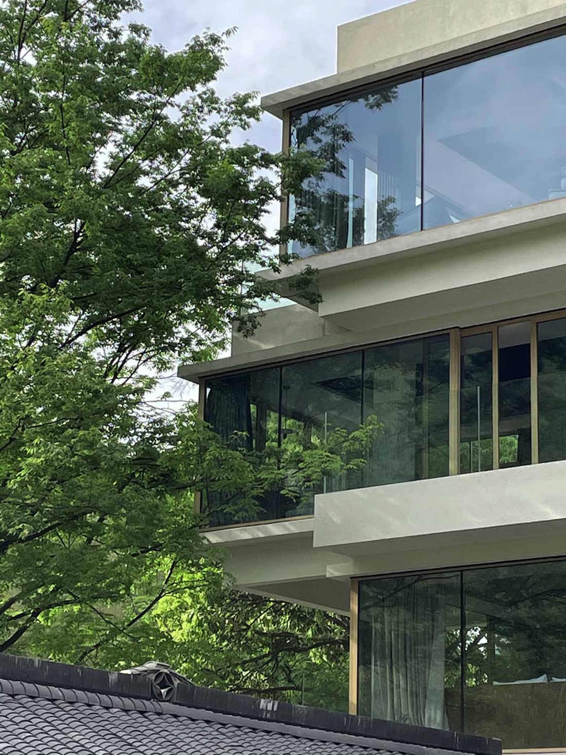 Modern residential exterior featuring glass, concrete, and metal materials.