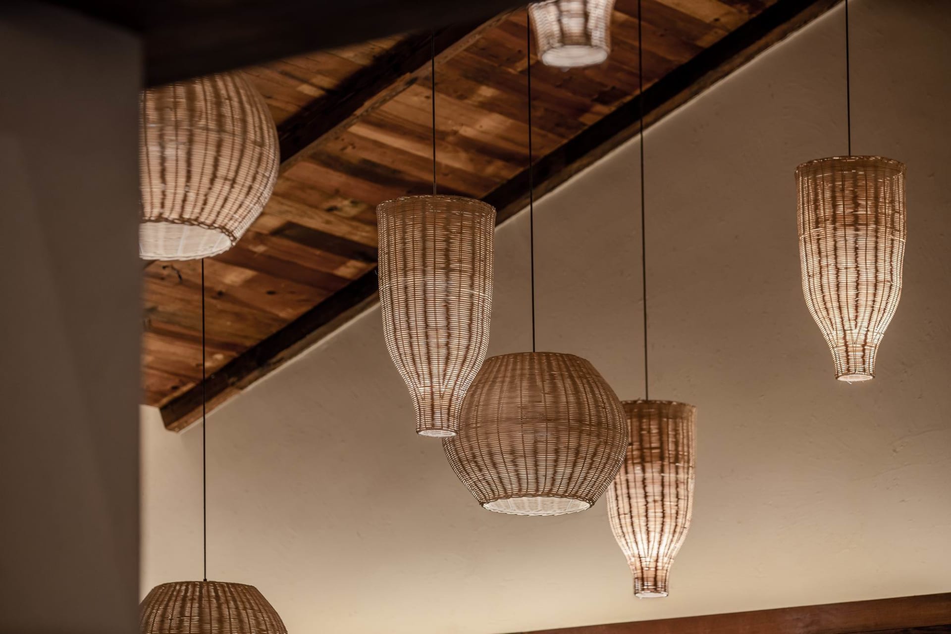 Multiple woven lighting lamps hanging indoors