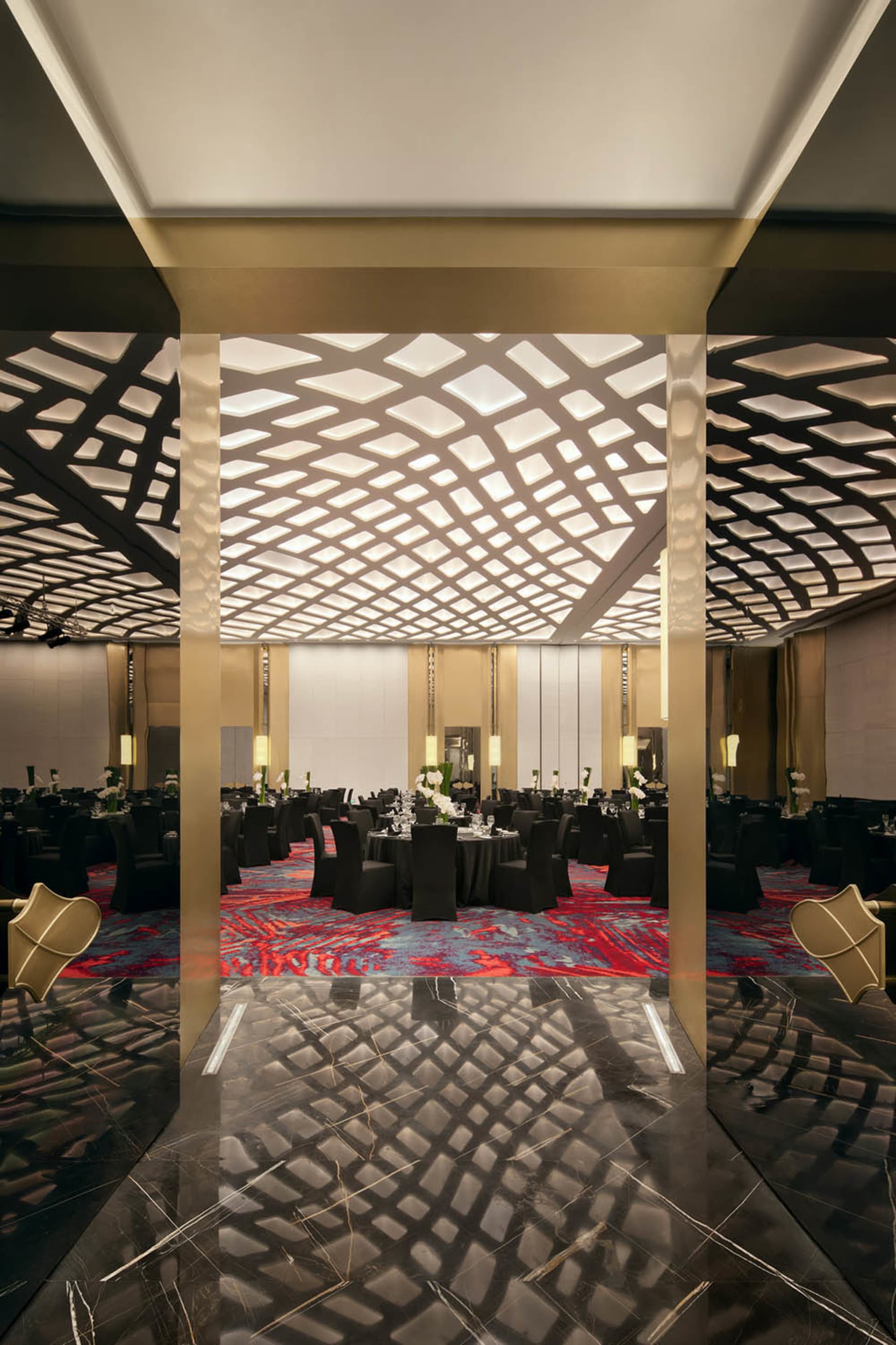 A grand ballroom featuring modern design with marble, metal, and glass elements.