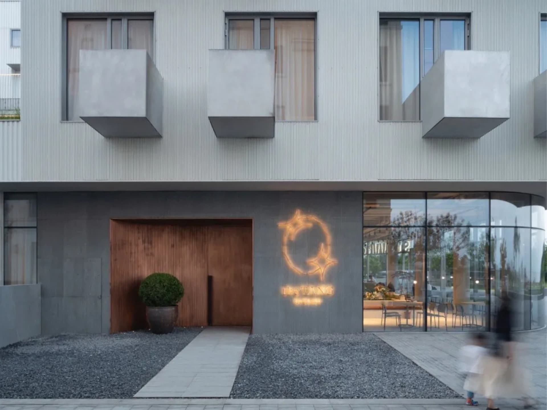 Modern storefront with concrete walls, glass windows, and a neon sign.