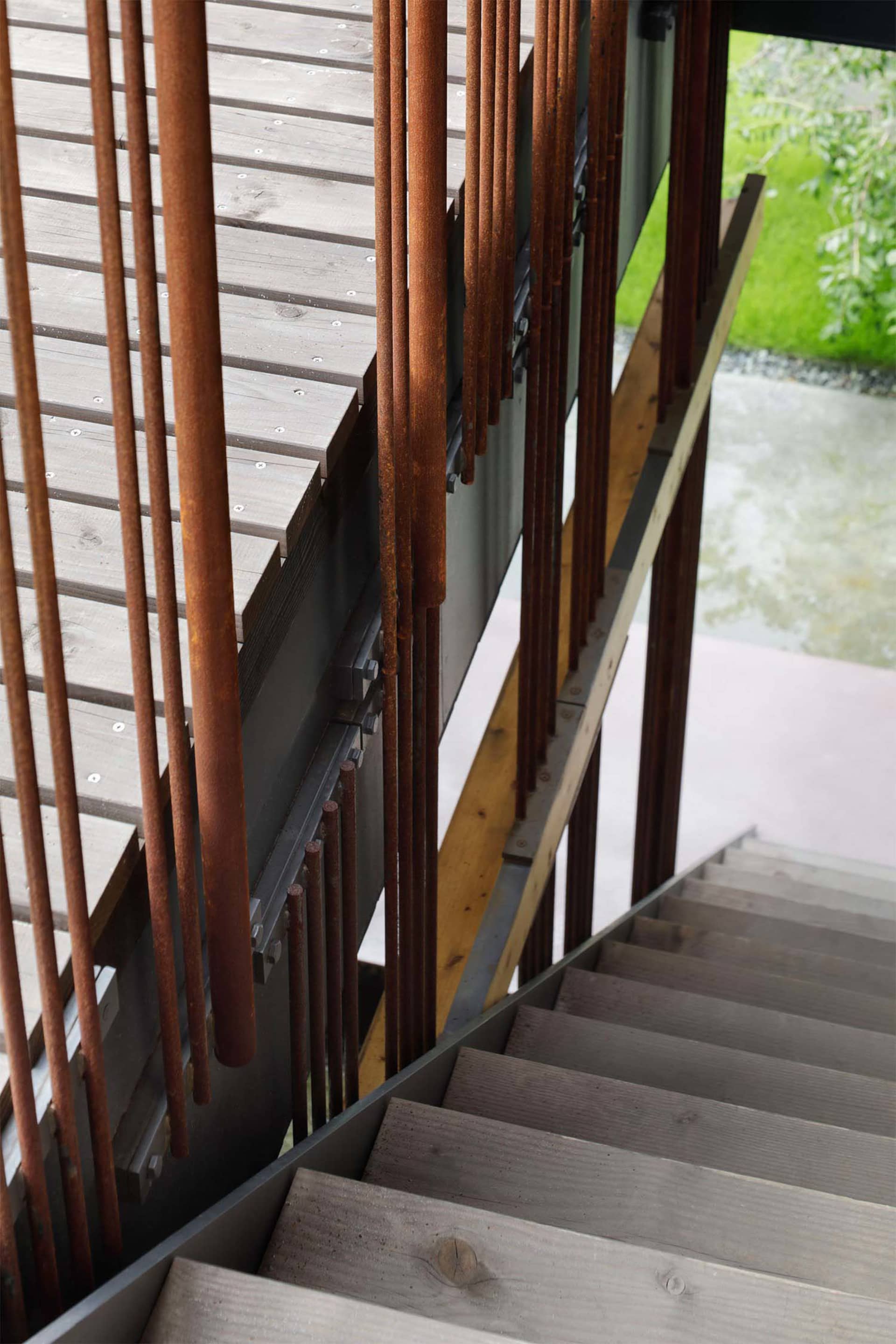An industrial-style staircase featuring wooden steps and steel railing.