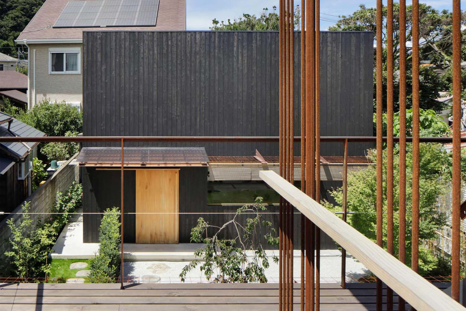 現代住宅建築,外牆採用黑色木板,搭配金屬屋頂,位於郊區環境中。