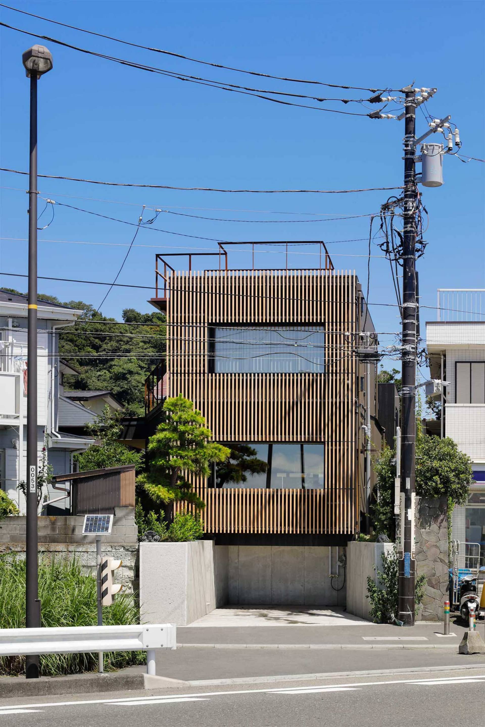 一座擁有木質外牆的現代住宅建築，設有屋頂露台，呈現簡約設計風格。