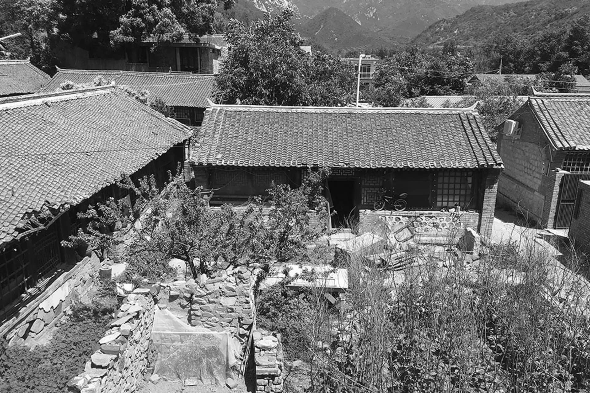一座被傳統建築與綠意環繞、擁有瓦片屋頂的庭院。