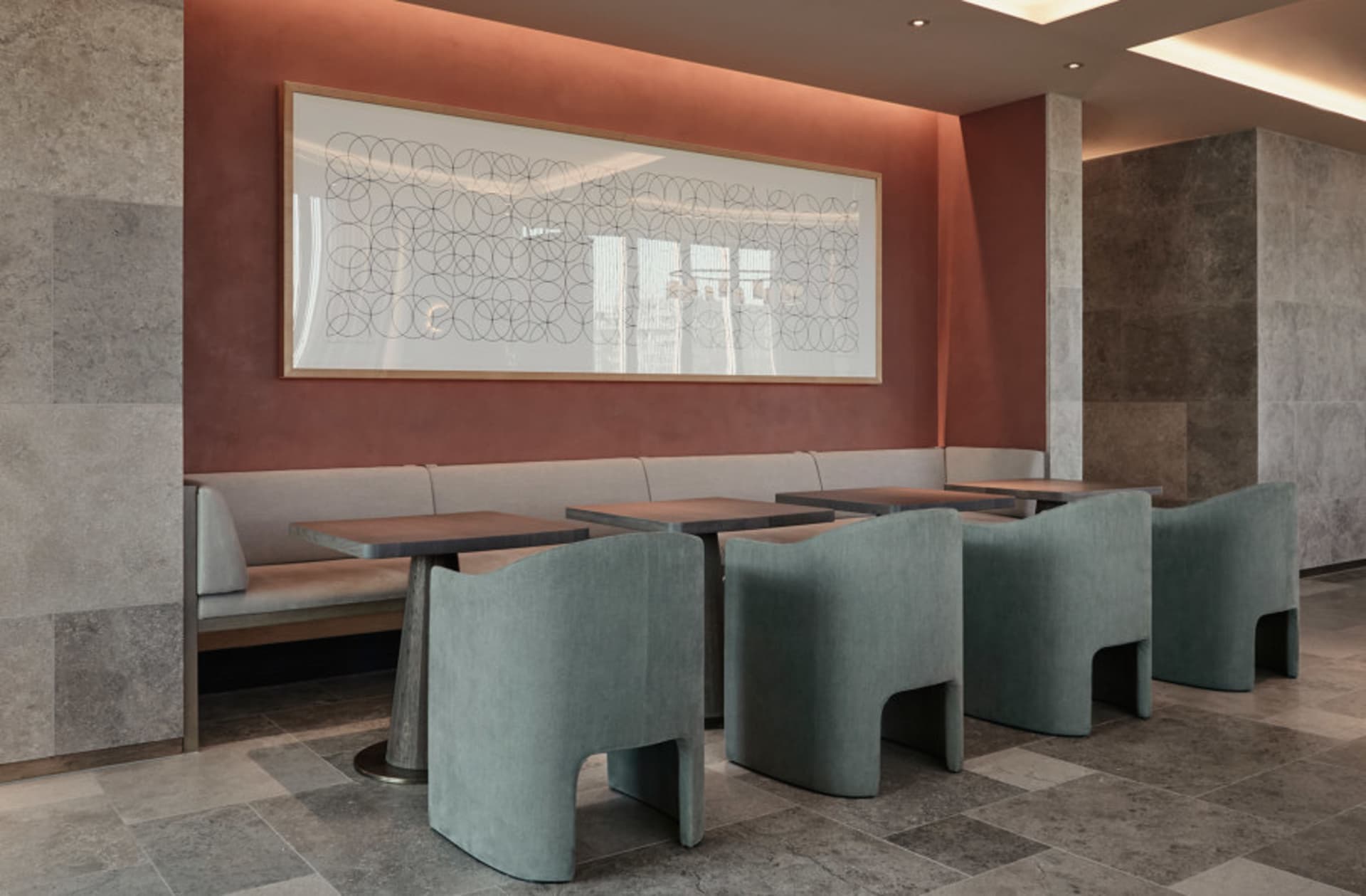 Seating area in an industrial-themed restaurant with concrete walls, chairs, and tables.