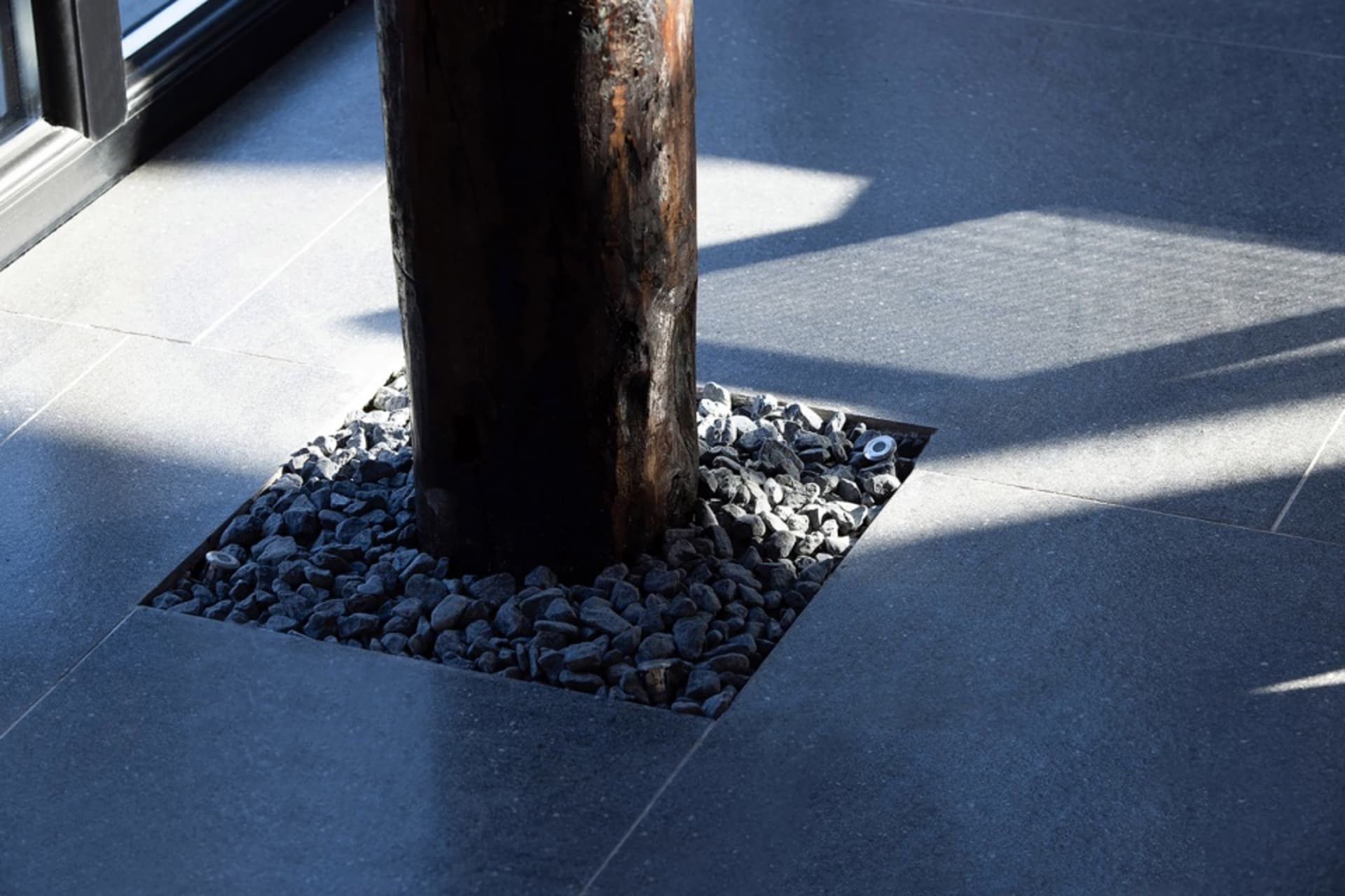 Modern lighting fixture installed on a concrete tile floor with geometric shadows.