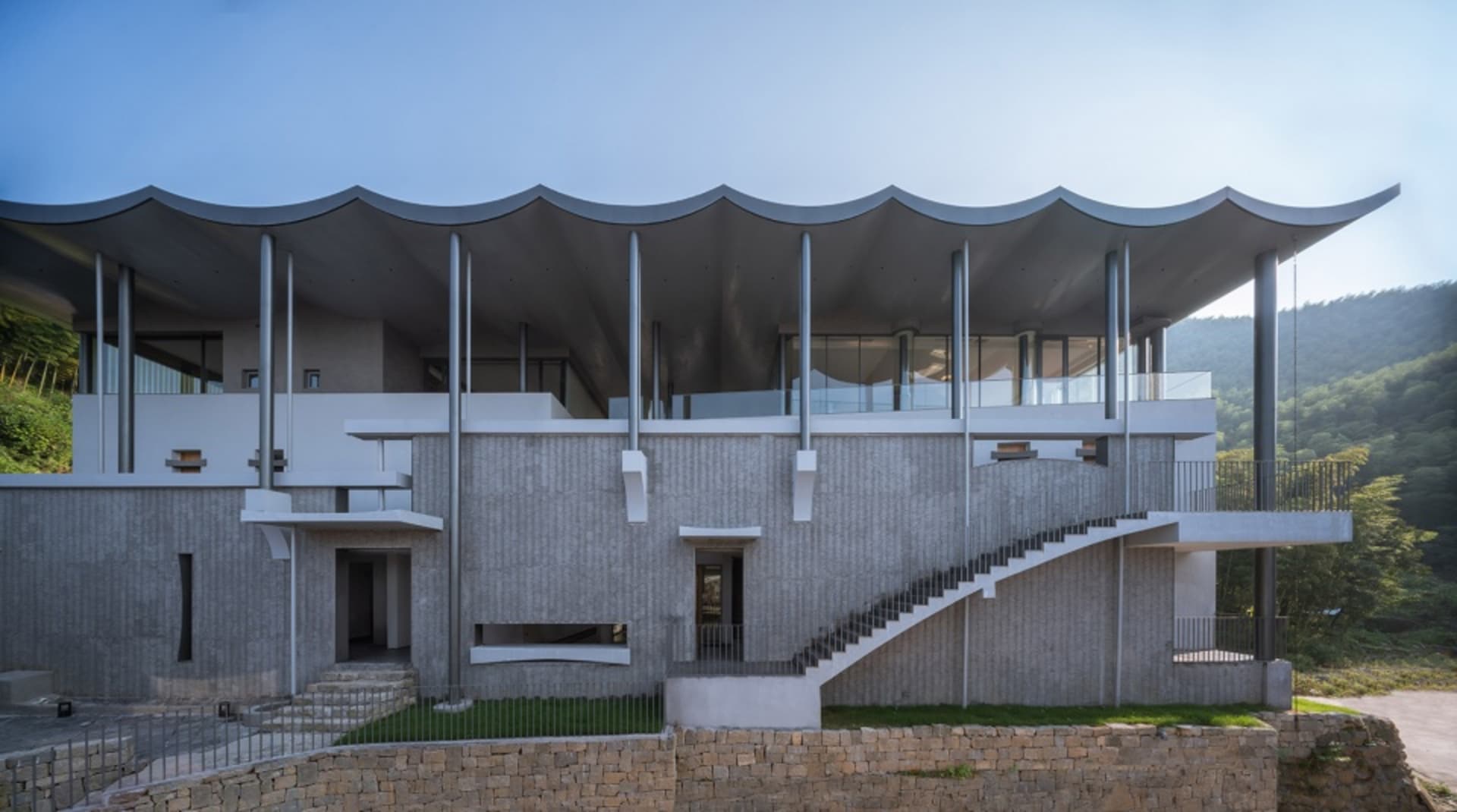 一座現代住宅建築,外牆採用混凝土材質並搭配大型玻璃面板。