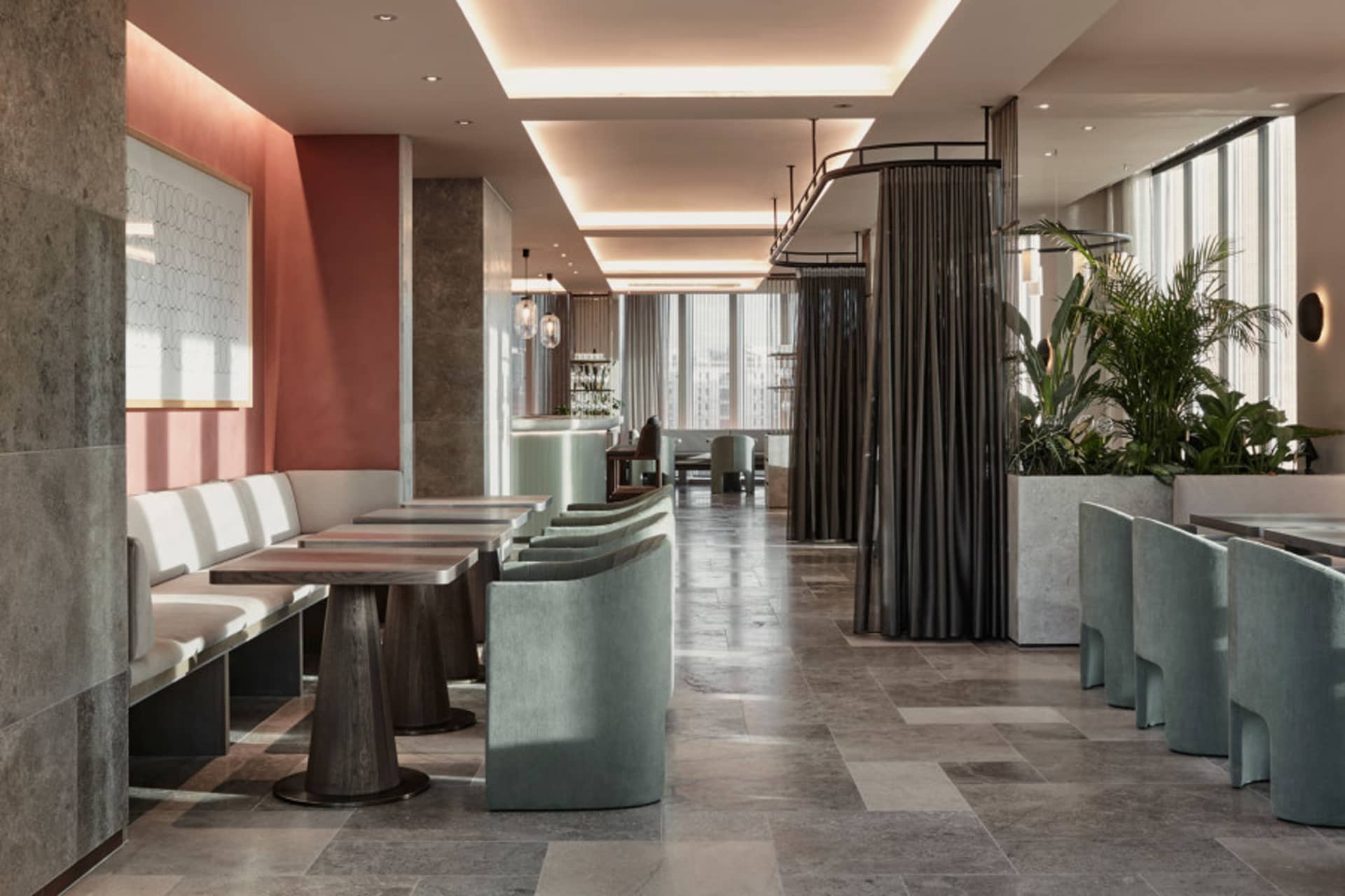Modern restaurant interior with concrete flooring, white seating, and green plants.