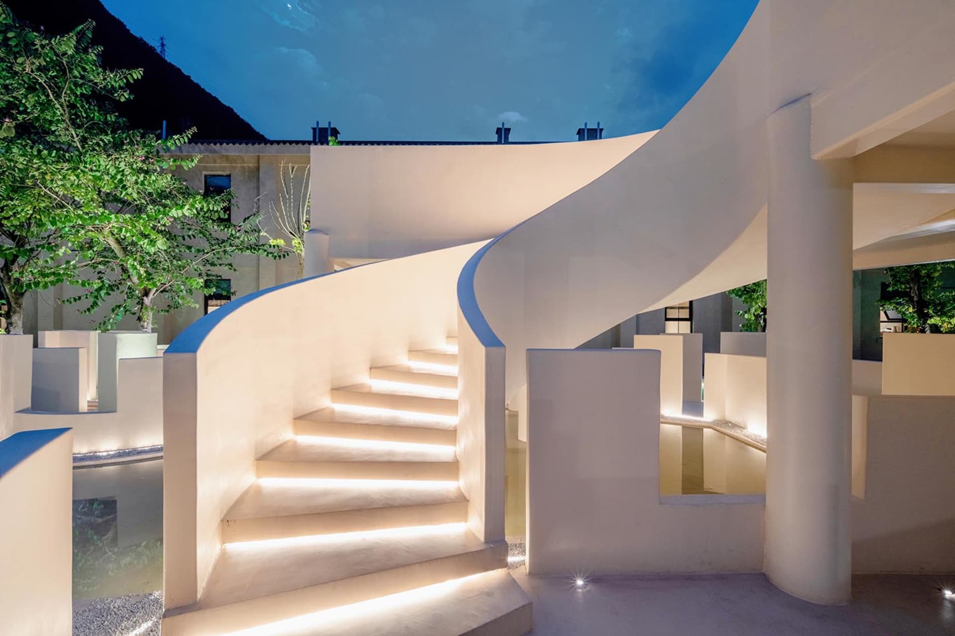 A modern sculpture space with illuminated elements and a curved staircase.