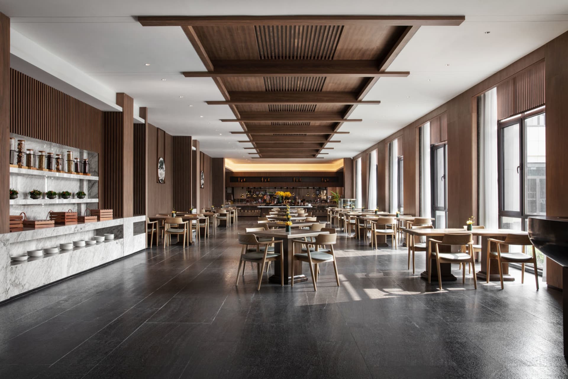 Industrial-style restaurant interior with marble countertops, wooden tables, and metallic bar.