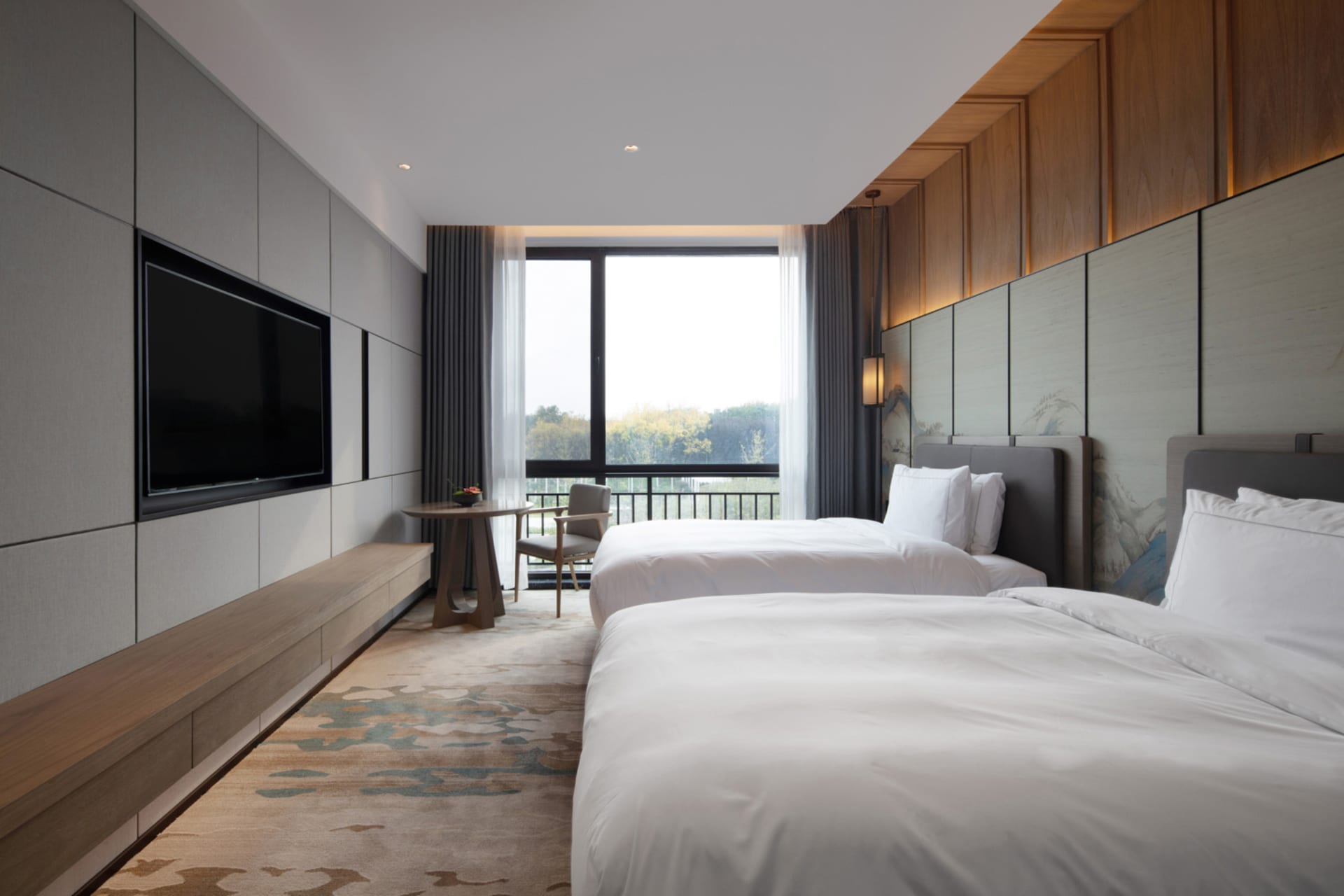 A modern bedroom with two twin beds, wooden headboards, and a television mounted on the wall.