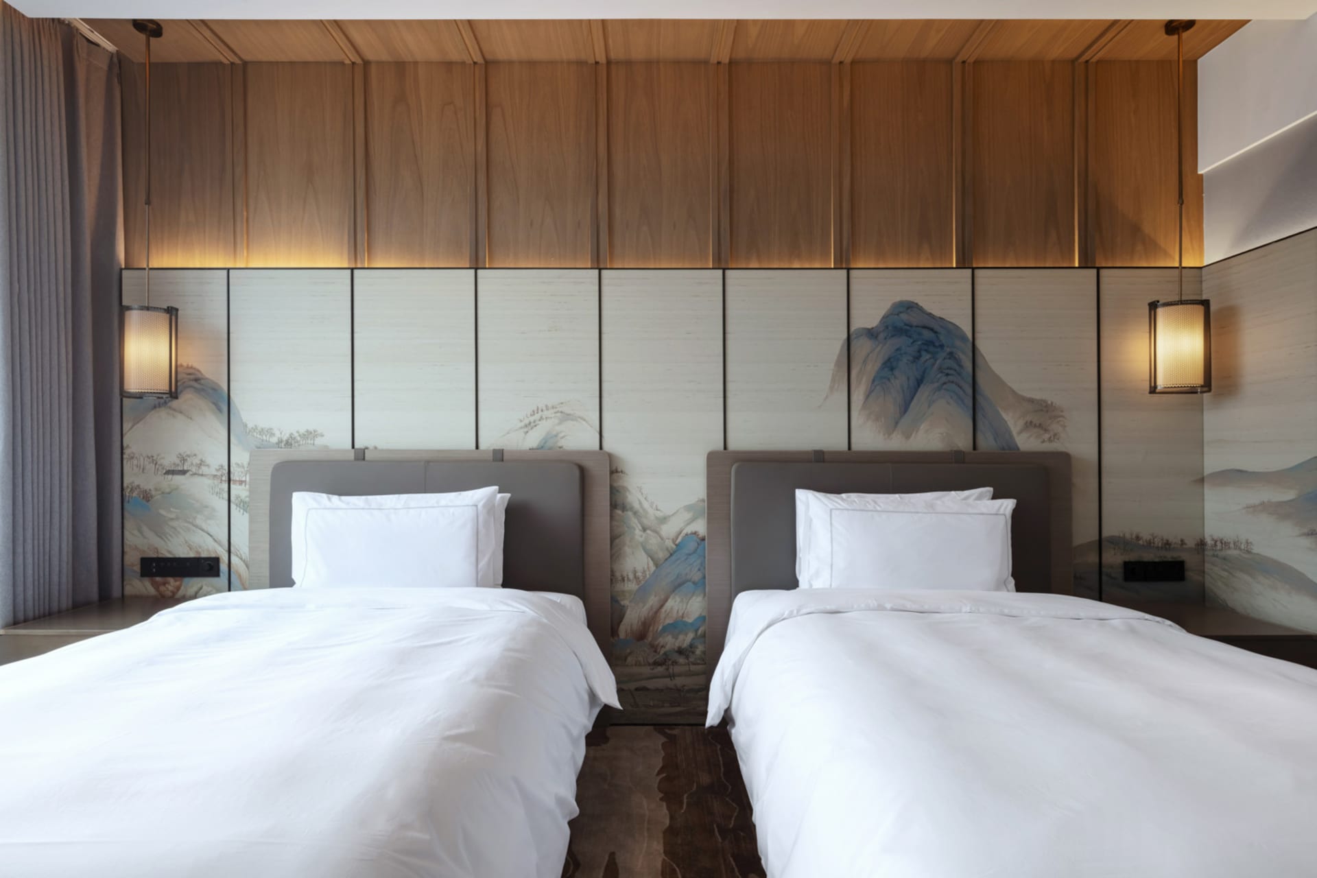A modern hotel room featuring wooden paneling and twin beds.