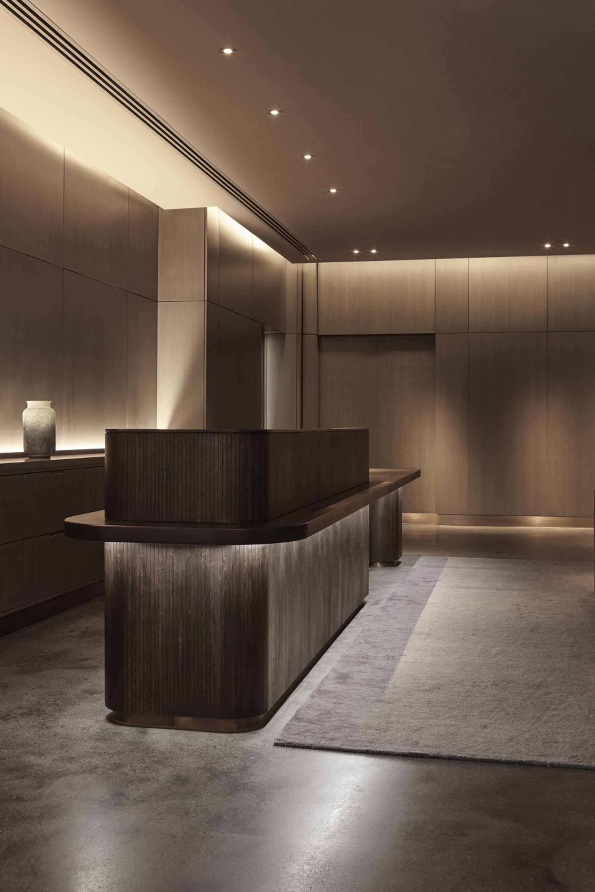 A modern interior reception area featuring a wooden desk and lighting.