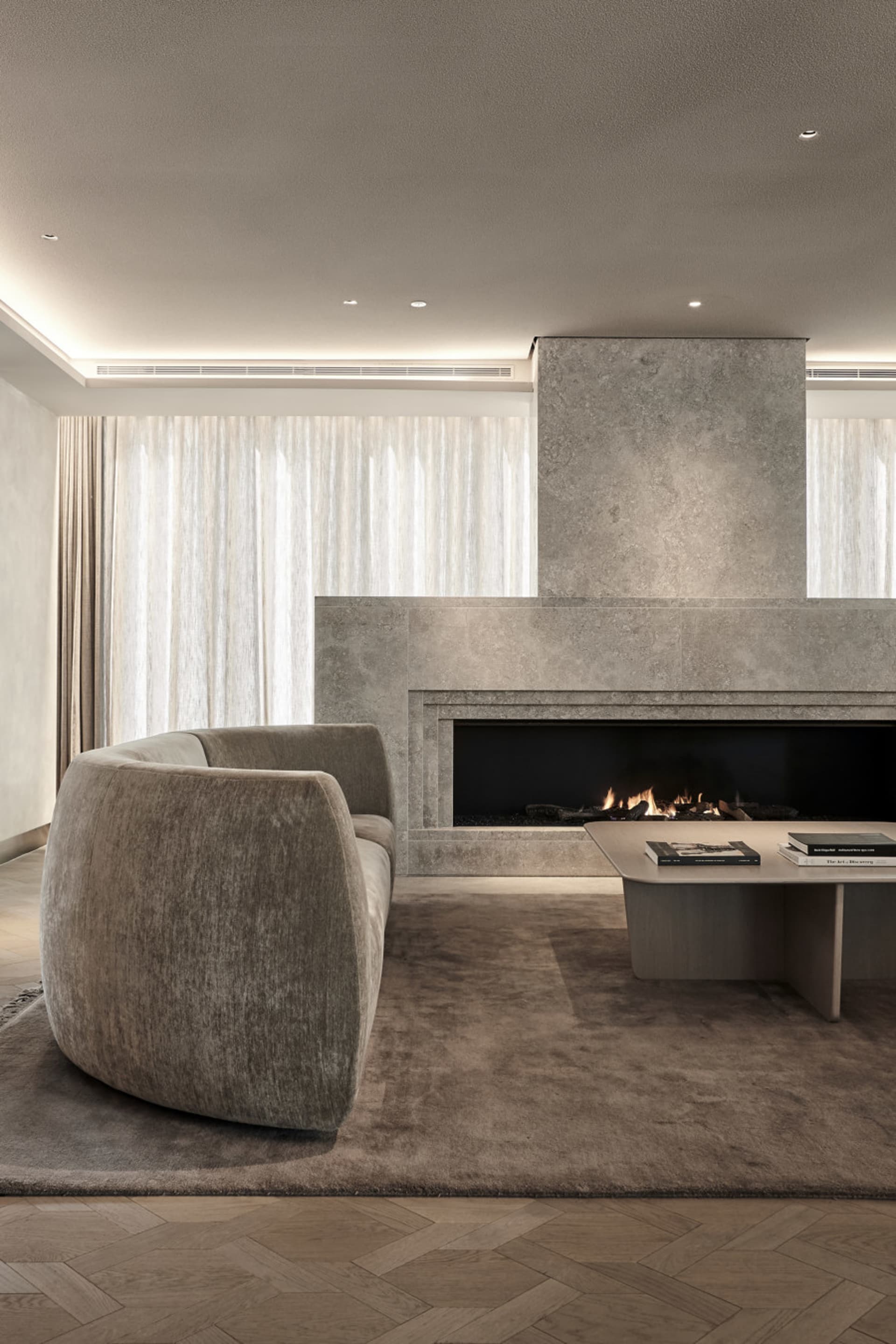 Modern minimalist living room featuring a concrete fireplace and neutral-colored furniture.
