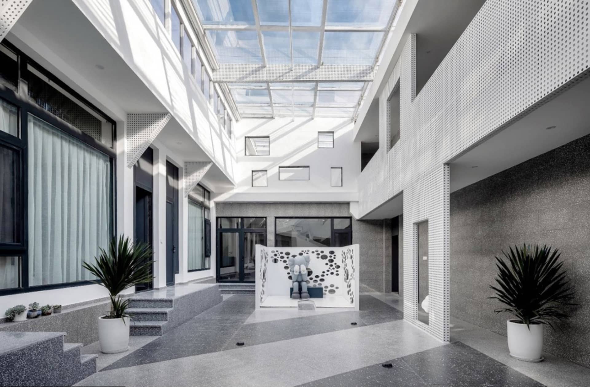 A minimalist modern residential interior with white ceramic tiles, granite walls, and large glass windows.