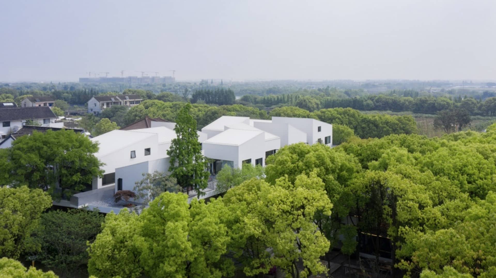 A modern white house surrounded by lush green trees.