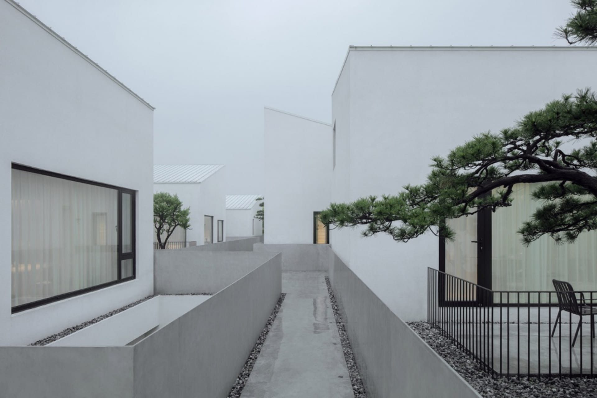 A serene, minimalist residential exterior composed of concrete materials with a quiet, natural atmosphere.