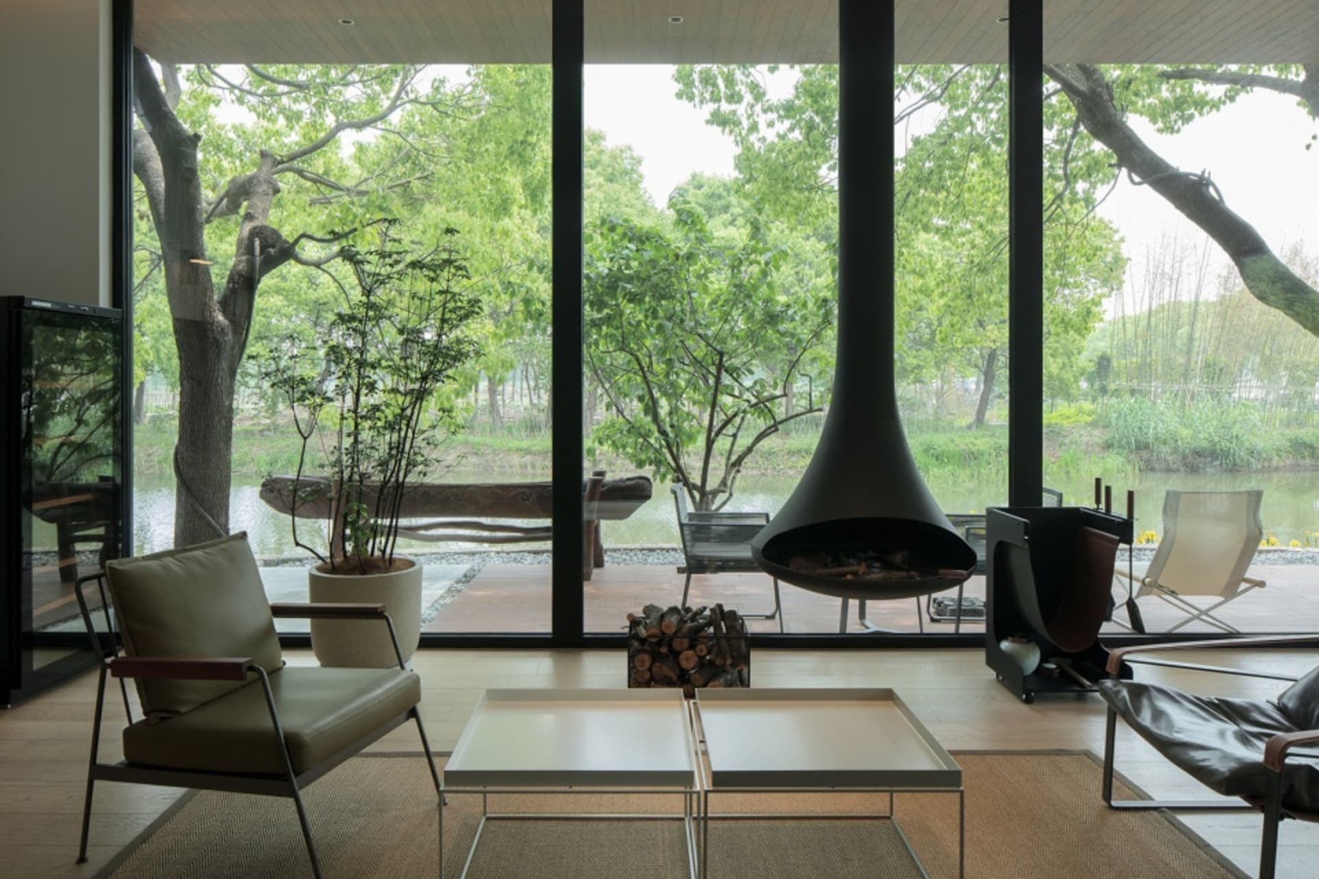 Modern living room featuring large glass windows overlooking a serene outdoor landscape.