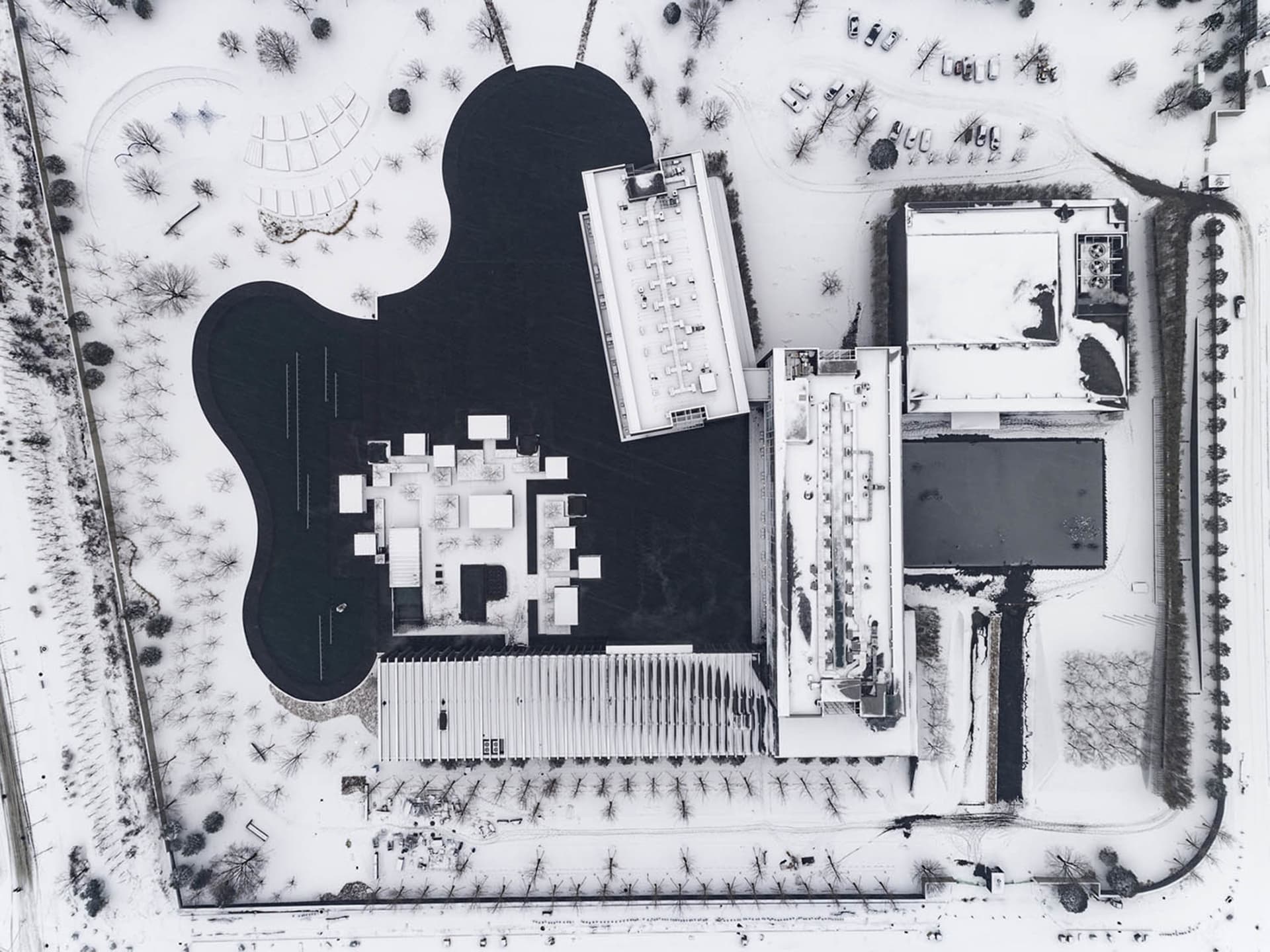 Aerial view of a modern building covered in snow with a minimalist architectural design.