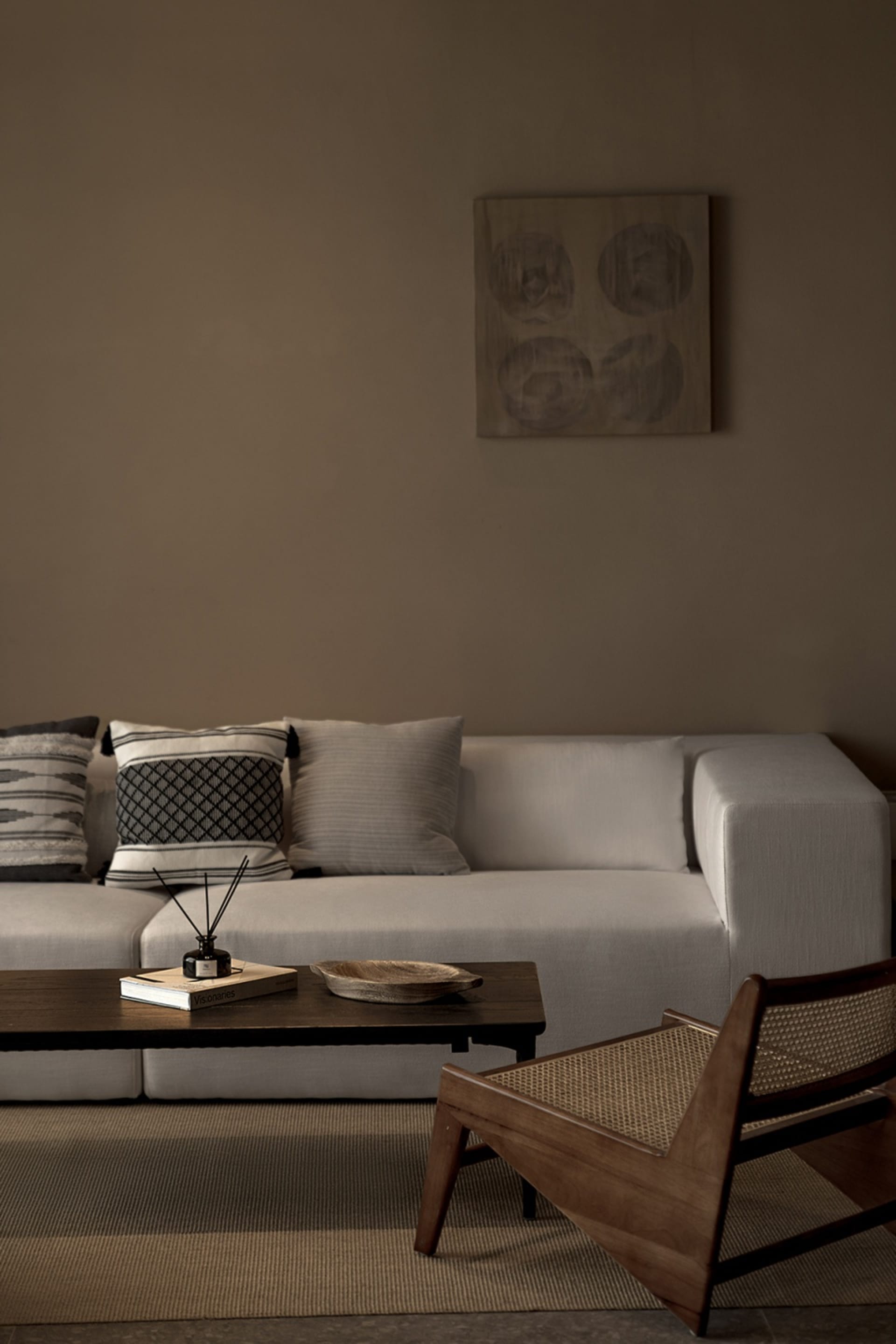 Industrial-style living room featuring a beige sectional sofa with fabric cushions, a wooden coffee table with a book and bow