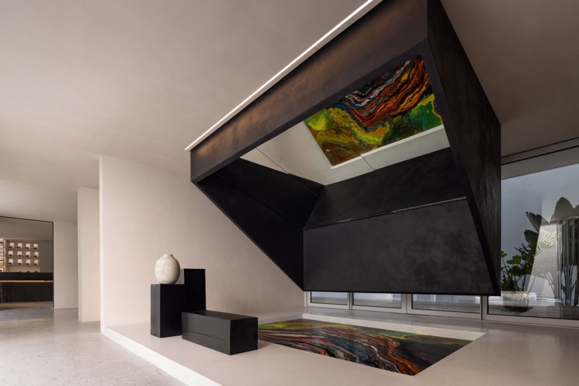 A modern interior featuring a black metal structure with a colorful abstract painting on the ceiling, set on a black tile pav