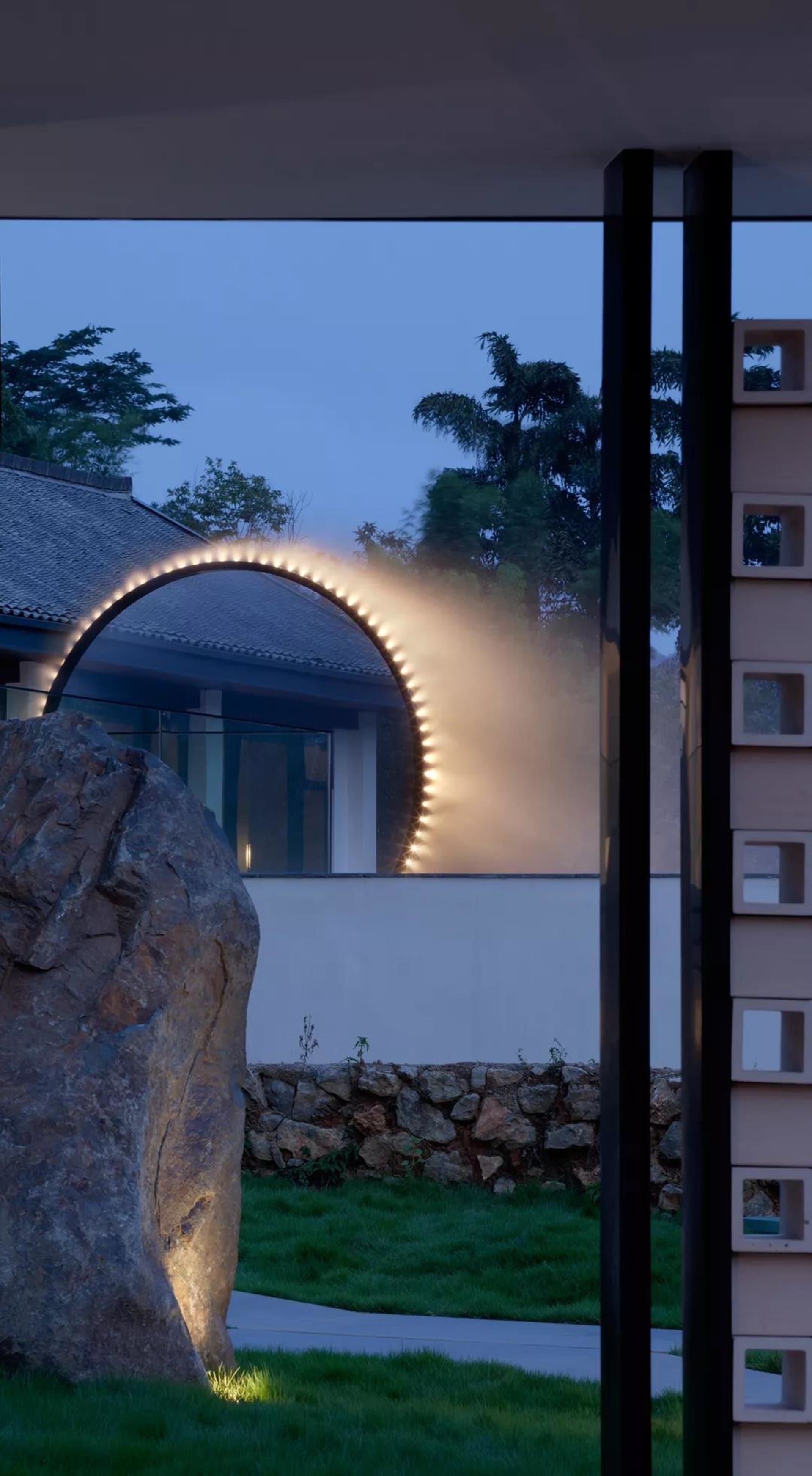 Modern architectural design featuring a concrete arch with integrated lighting at dusk