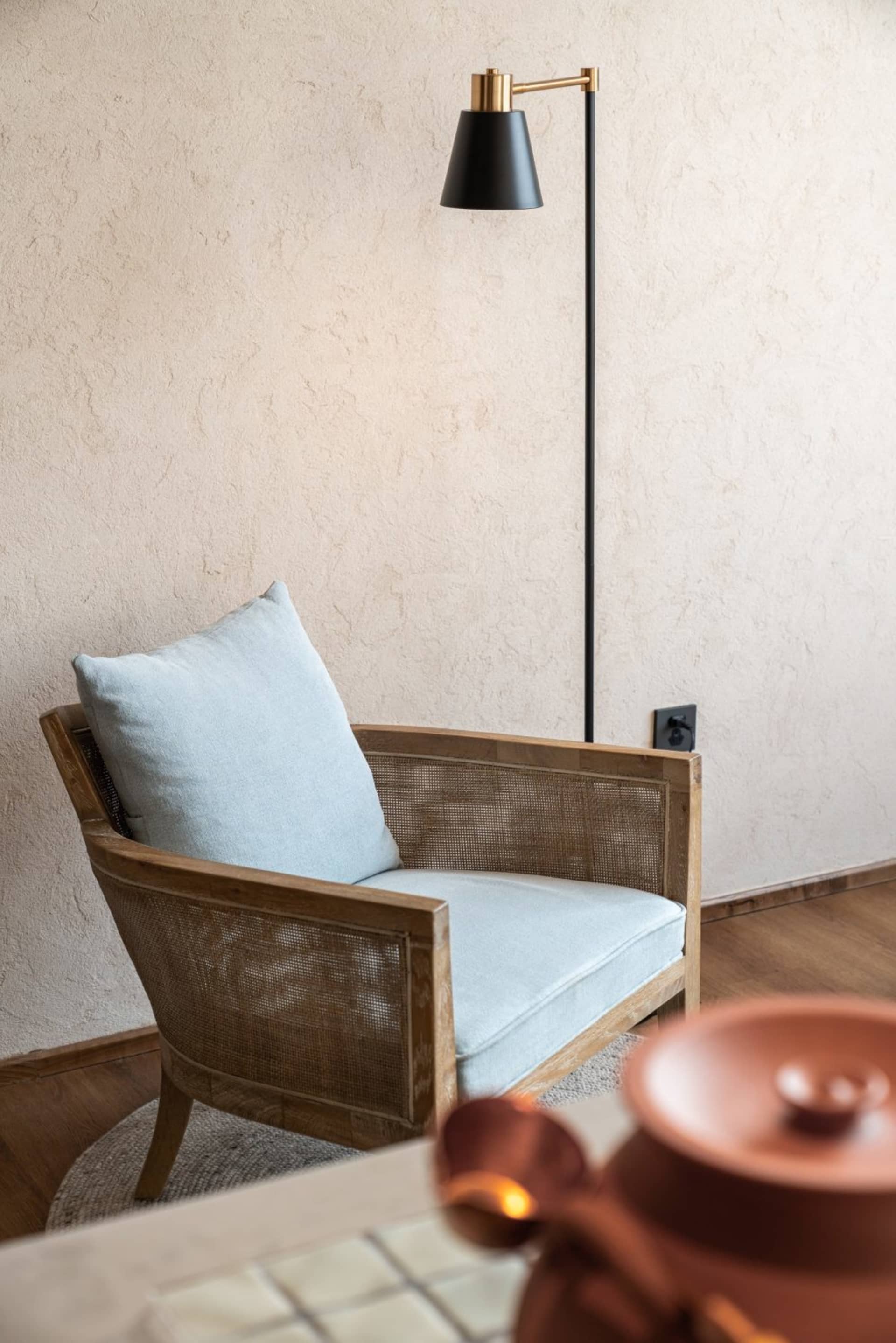 Modern living room with blue cushioned armchair, wooden legs, and floor lamp