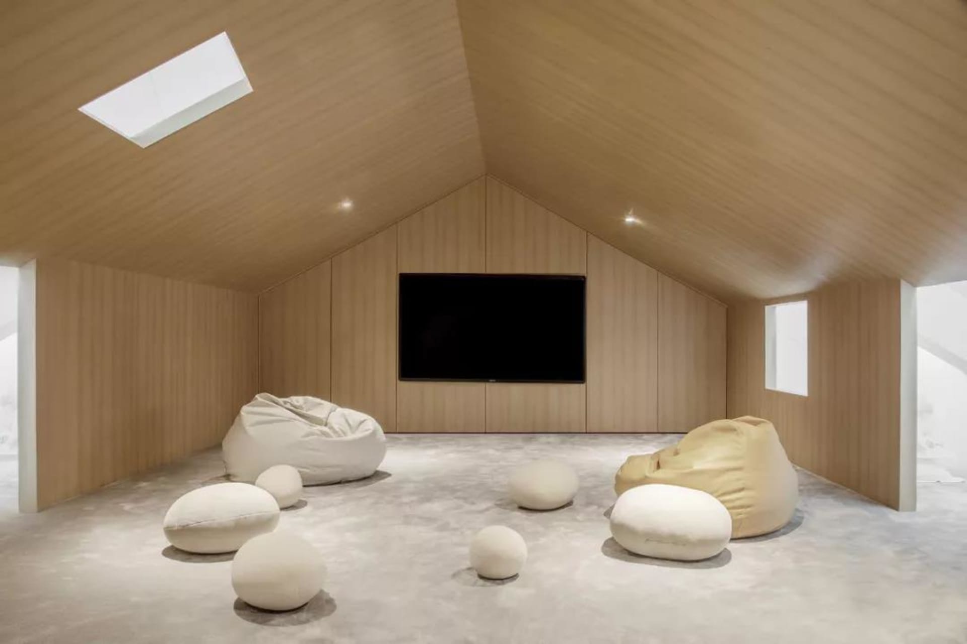 A minimalist living room with a wooden ceiling and floor, featuring a beanbag furniture set.