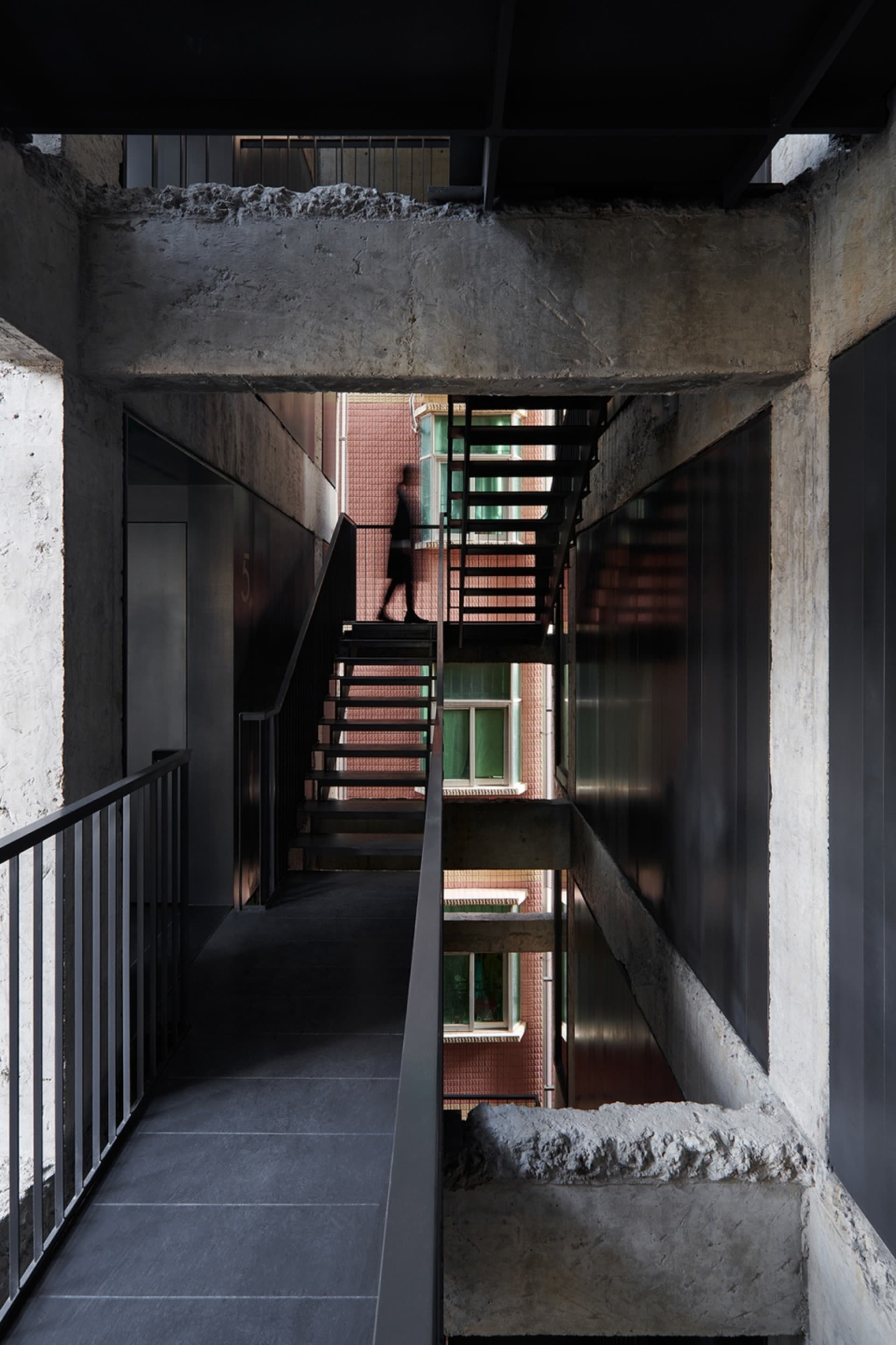 Concrete staircase with steel railings and a person walking up it.