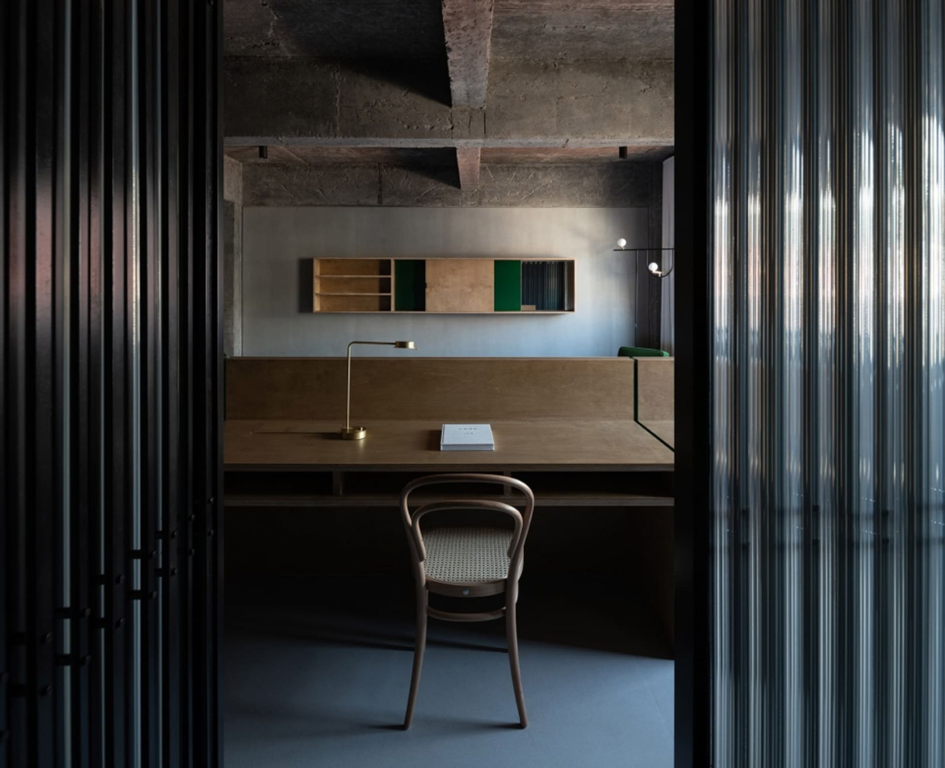 Industrial-style workspace featuring a wooden desk, chair, and minimalist shelving unit.
