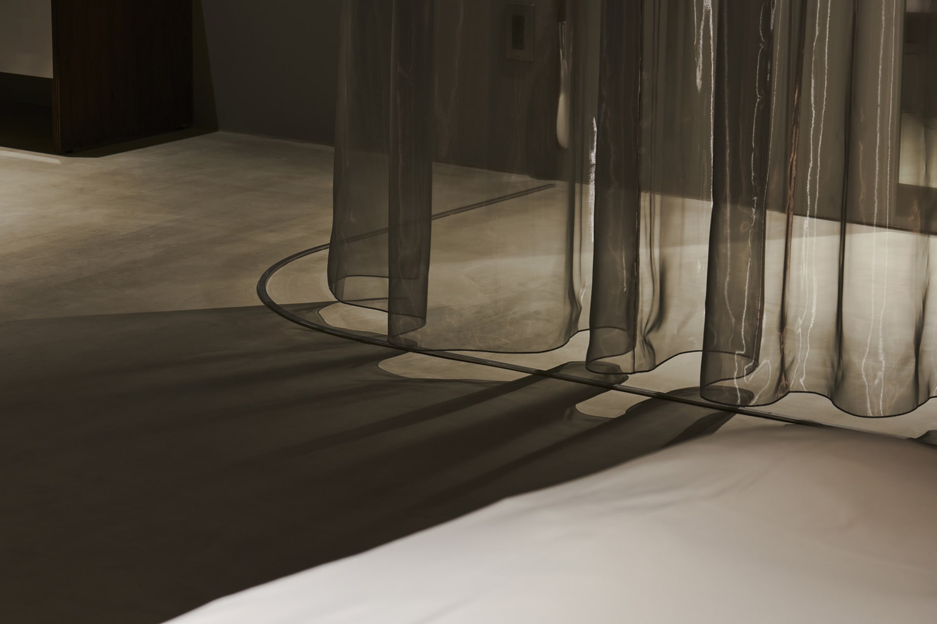 A minimalist interior with transparent curtains allowing natural light to filter through.