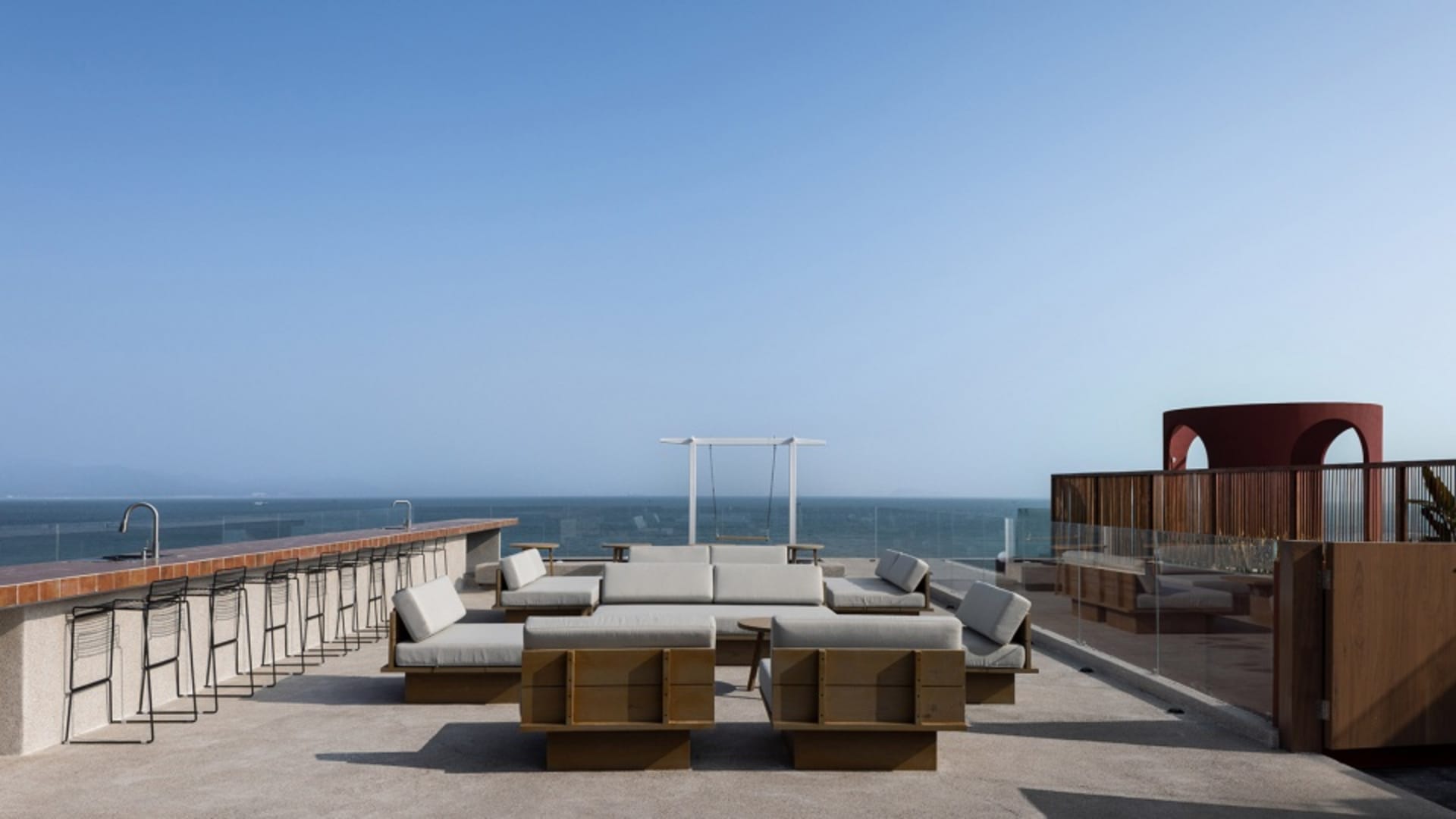 Contemporary rooftop bar with concrete flooring, bar stools, and seating areas