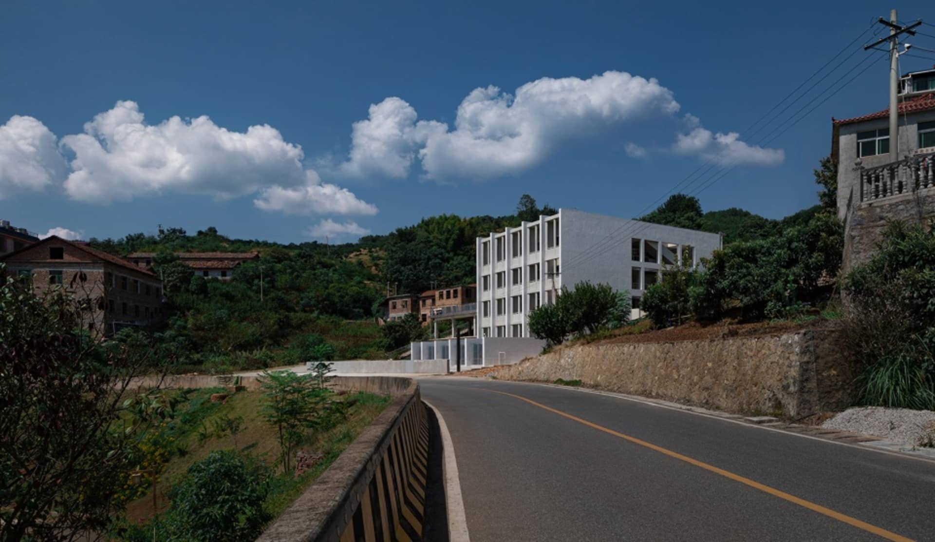 路邊混凝土與瀝青施工現場,背景有建築物與樹木。