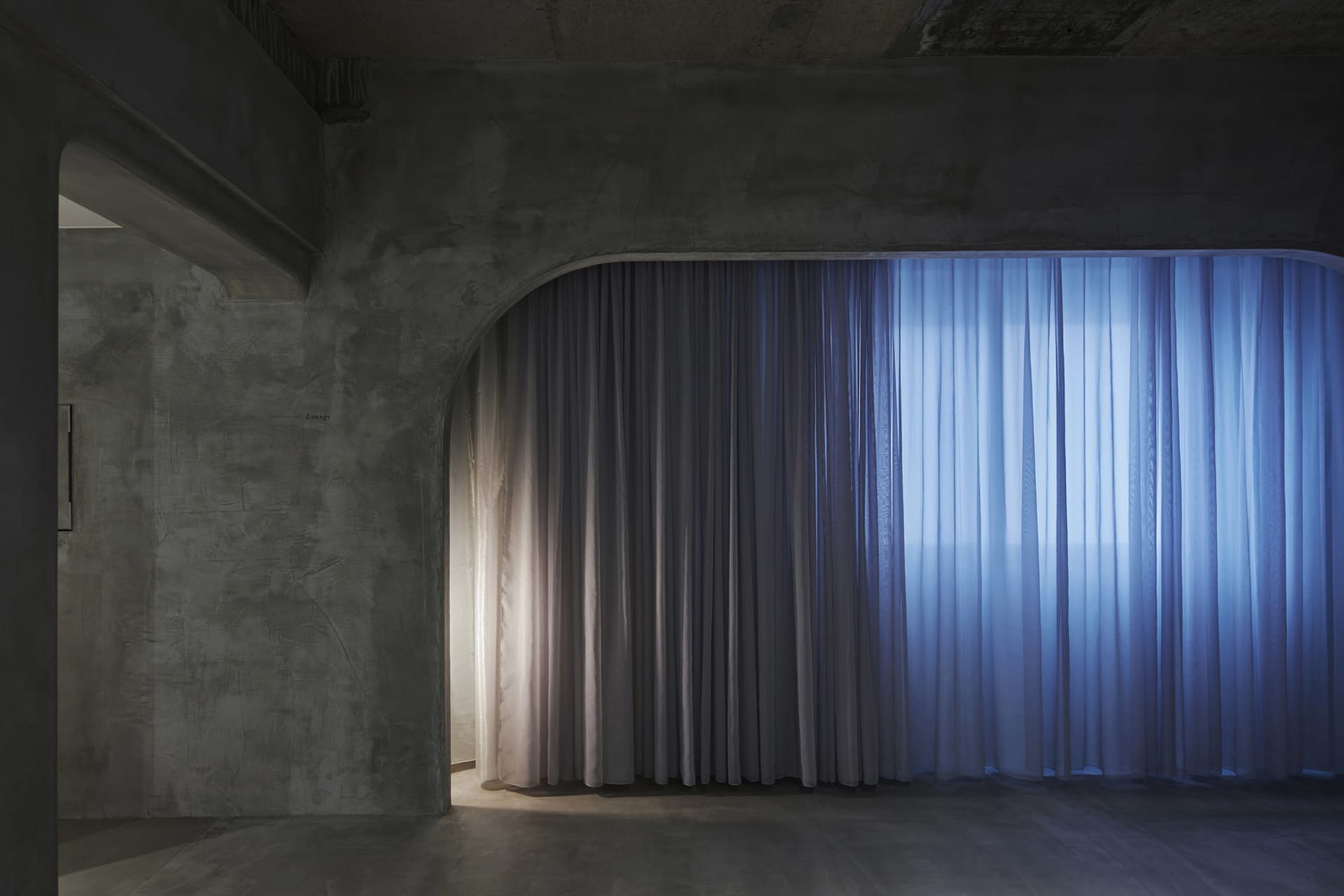 A modern interior design featuring luxurious drapery and concrete architectural elements.