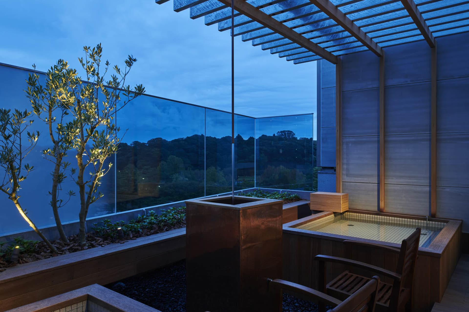 Modern balcony featuring glass windows and a wooden pergola at dusk.
