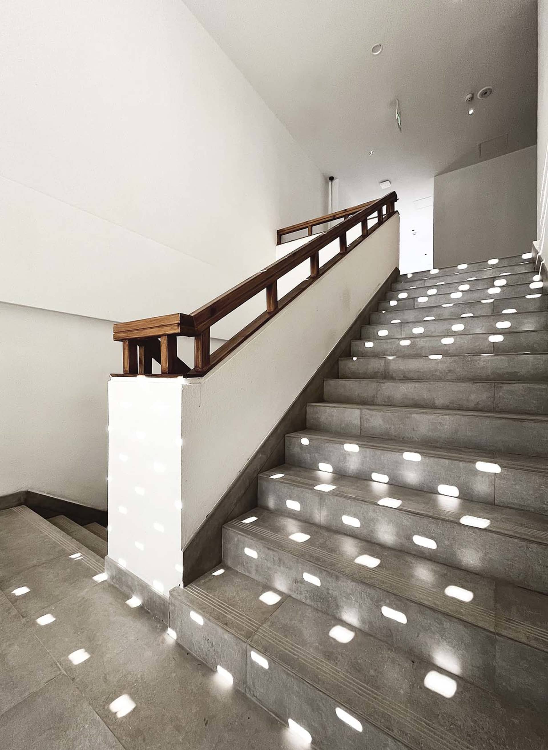 A modern industrial-style lobby with concrete stairs and flooring.