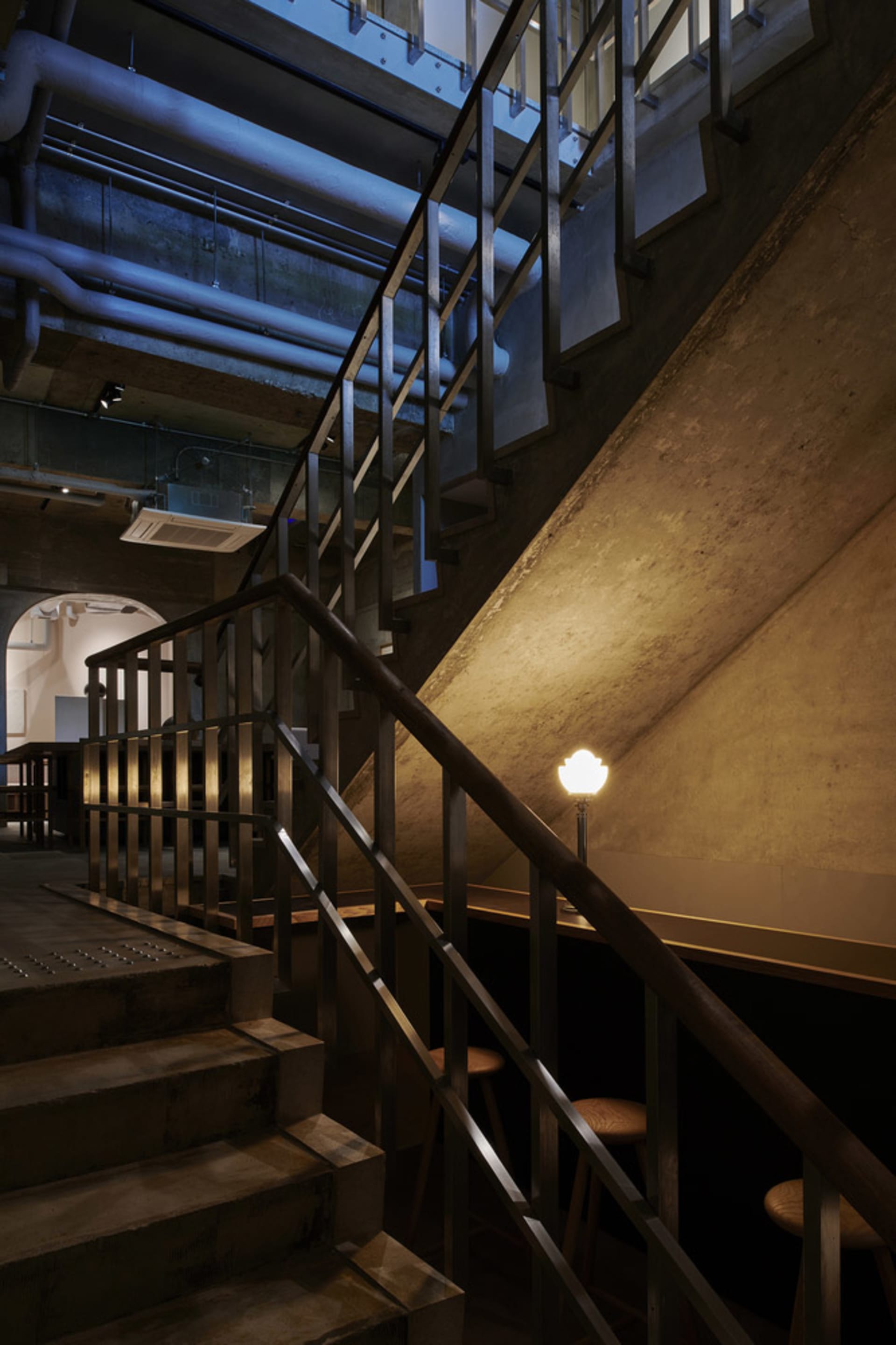 Concrete staircase with stainless steel railing in an industrial interior design setting.