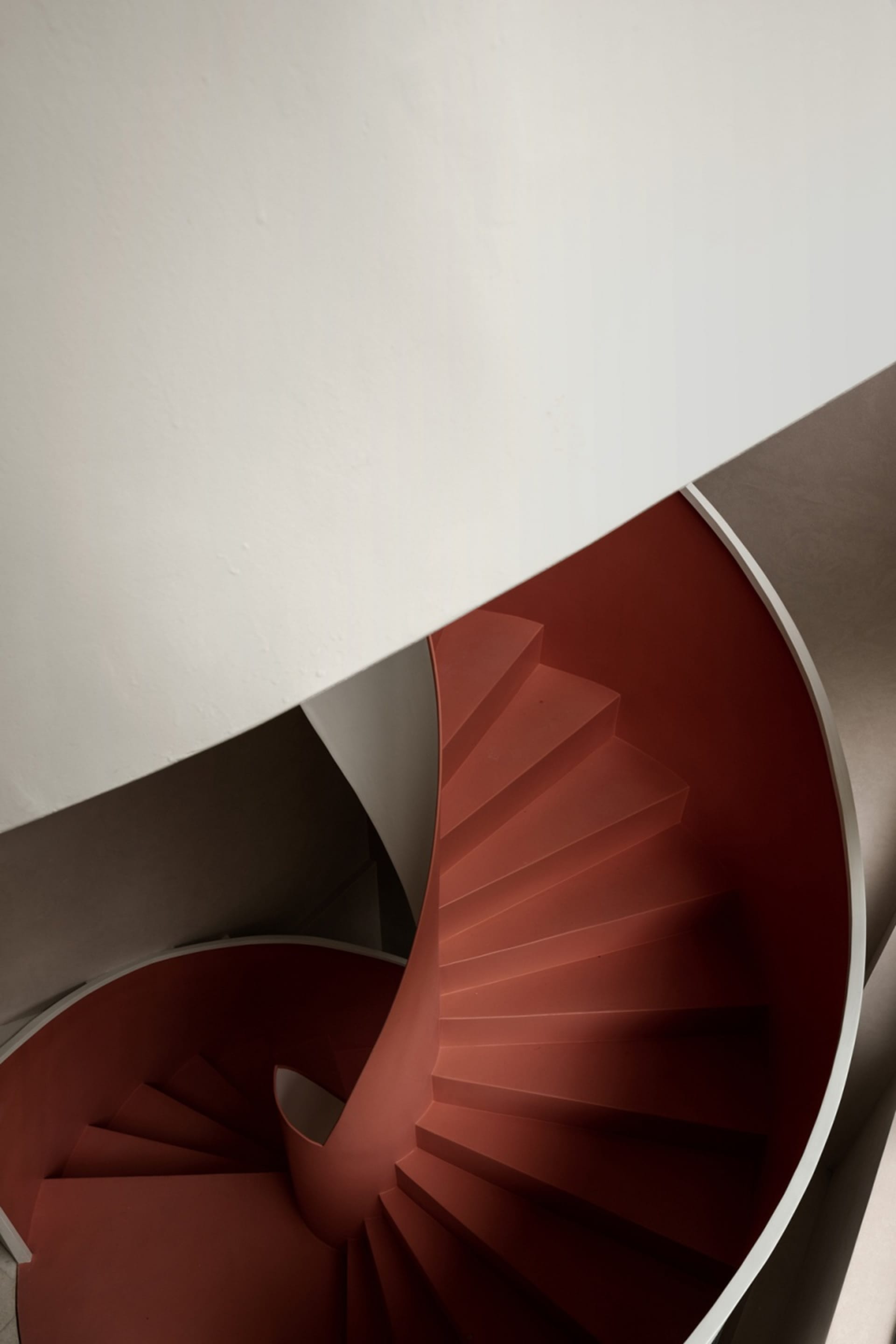 A spiral staircase with red steps inside a building.