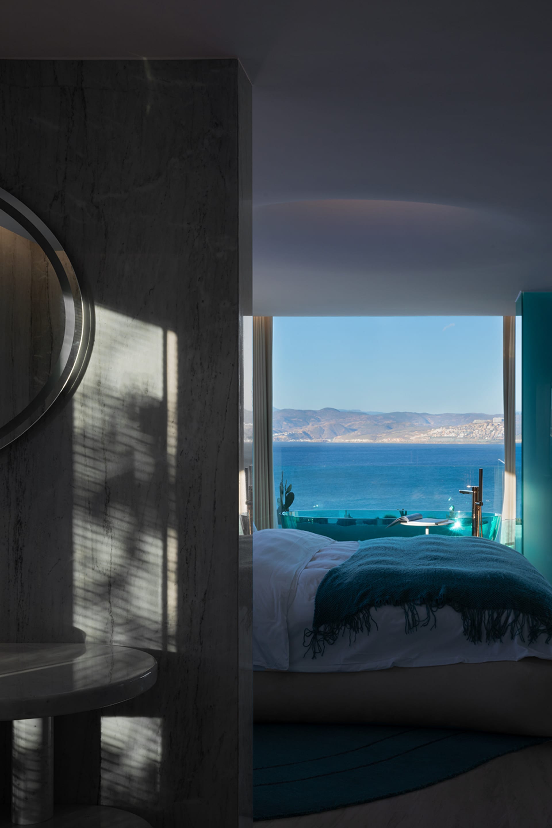 A stylish hotel room with a modern marble design, featuring a view of the ocean.