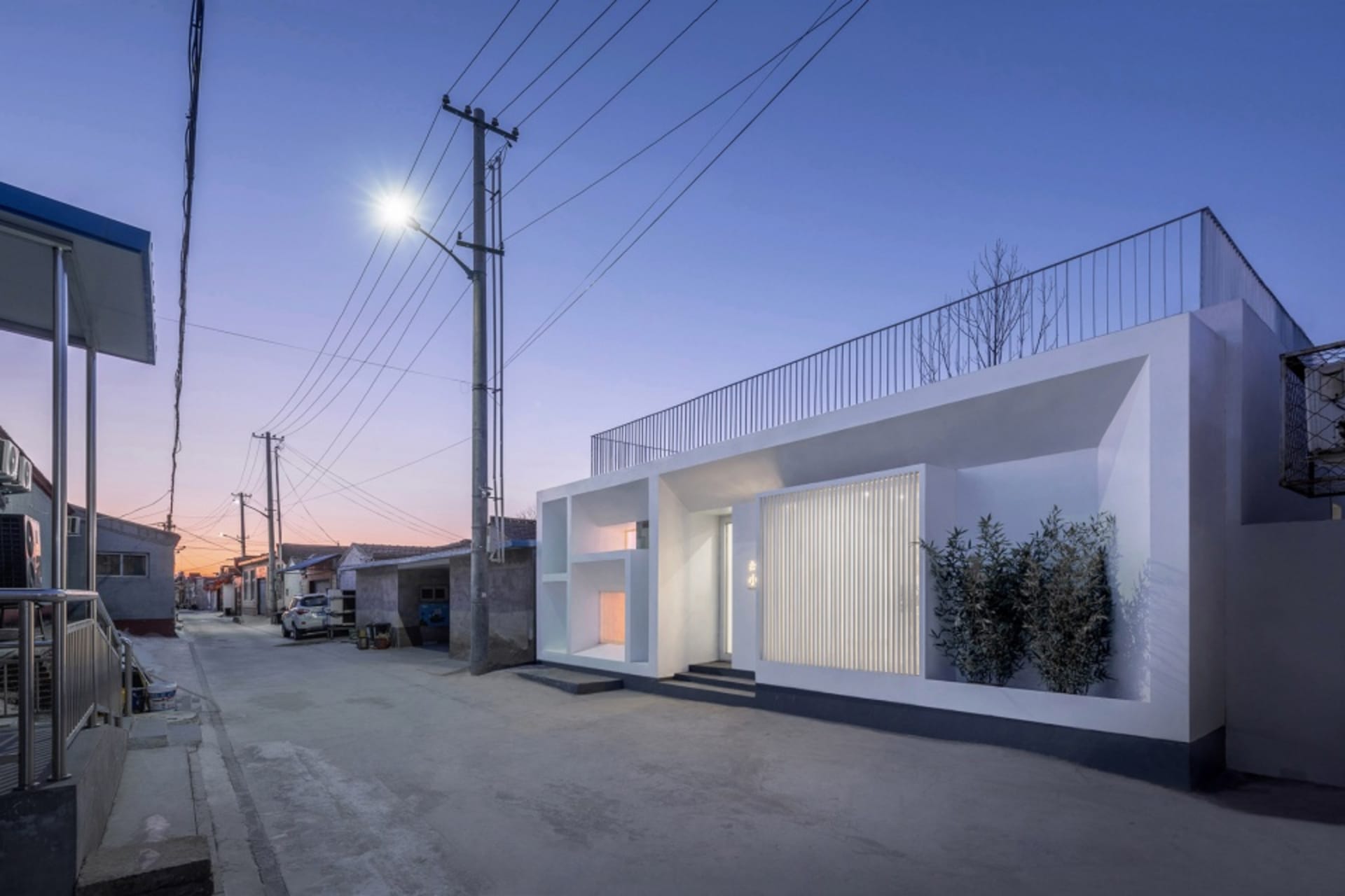 現代極簡住宅,搭配混凝土框架與金屬欄杆,在黃昏時分由街燈照亮。