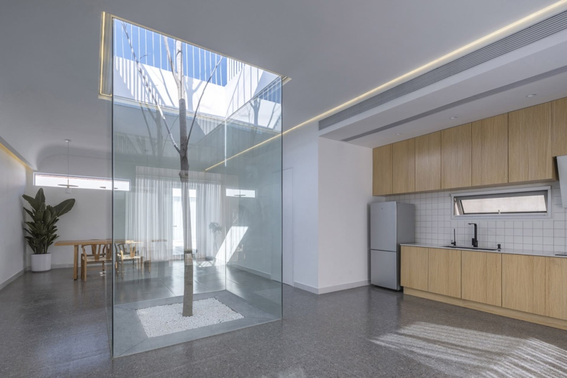 Modern minimalist kitchen with glass walls and wooden cabinets.