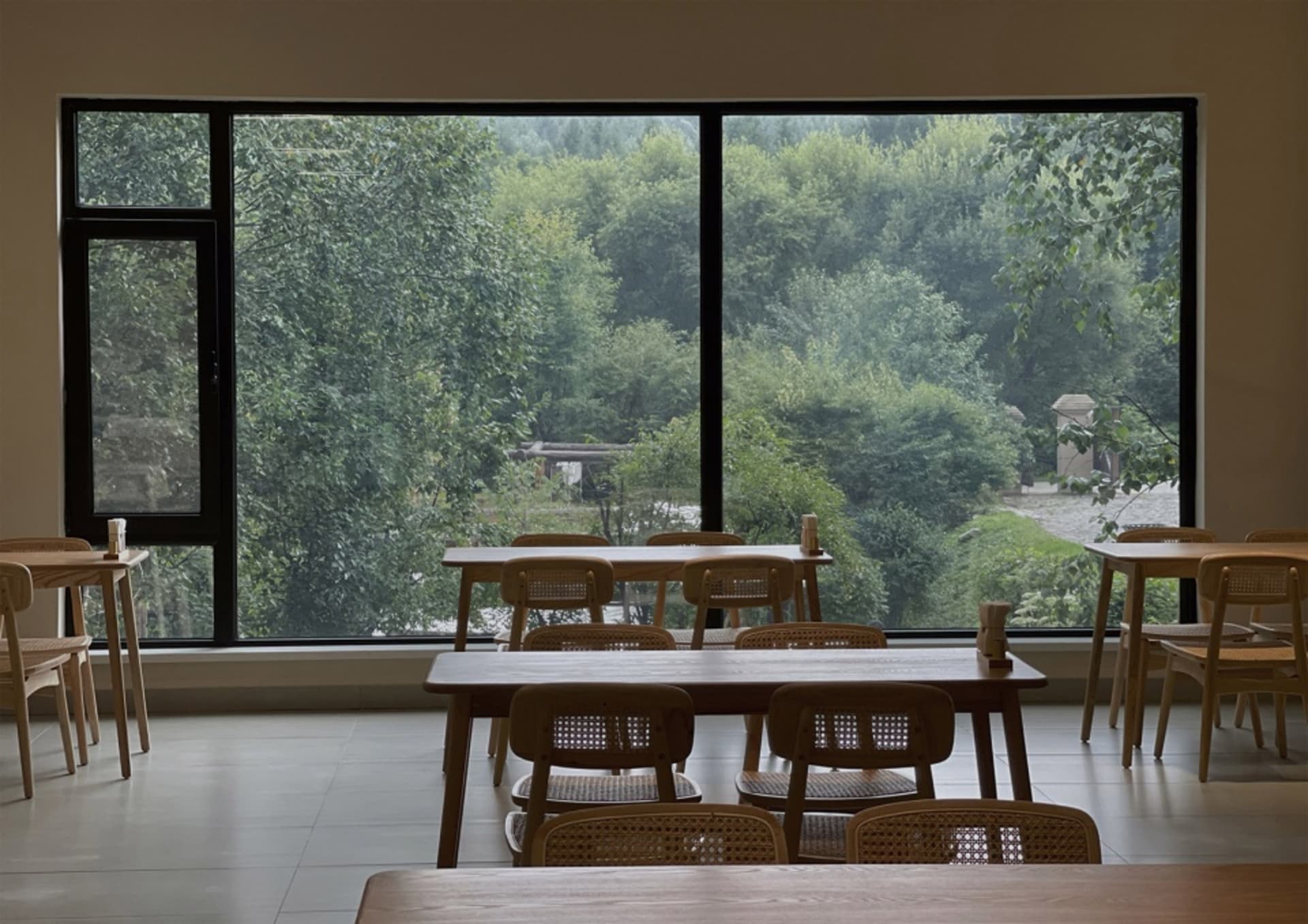A minimalistic restaurant interior with wooden tables and chairs.